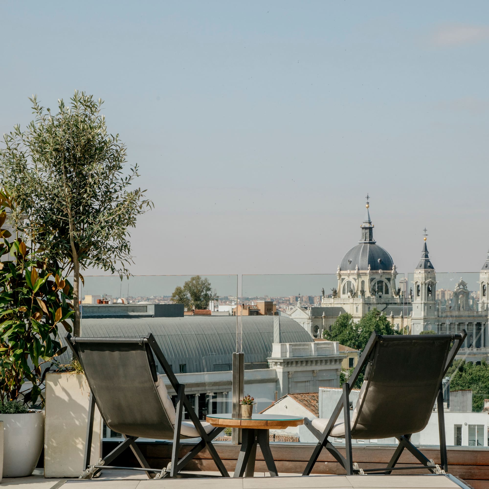 Madrid rooftop terrace with chairs, plants, and Almudena Cathedral view.
