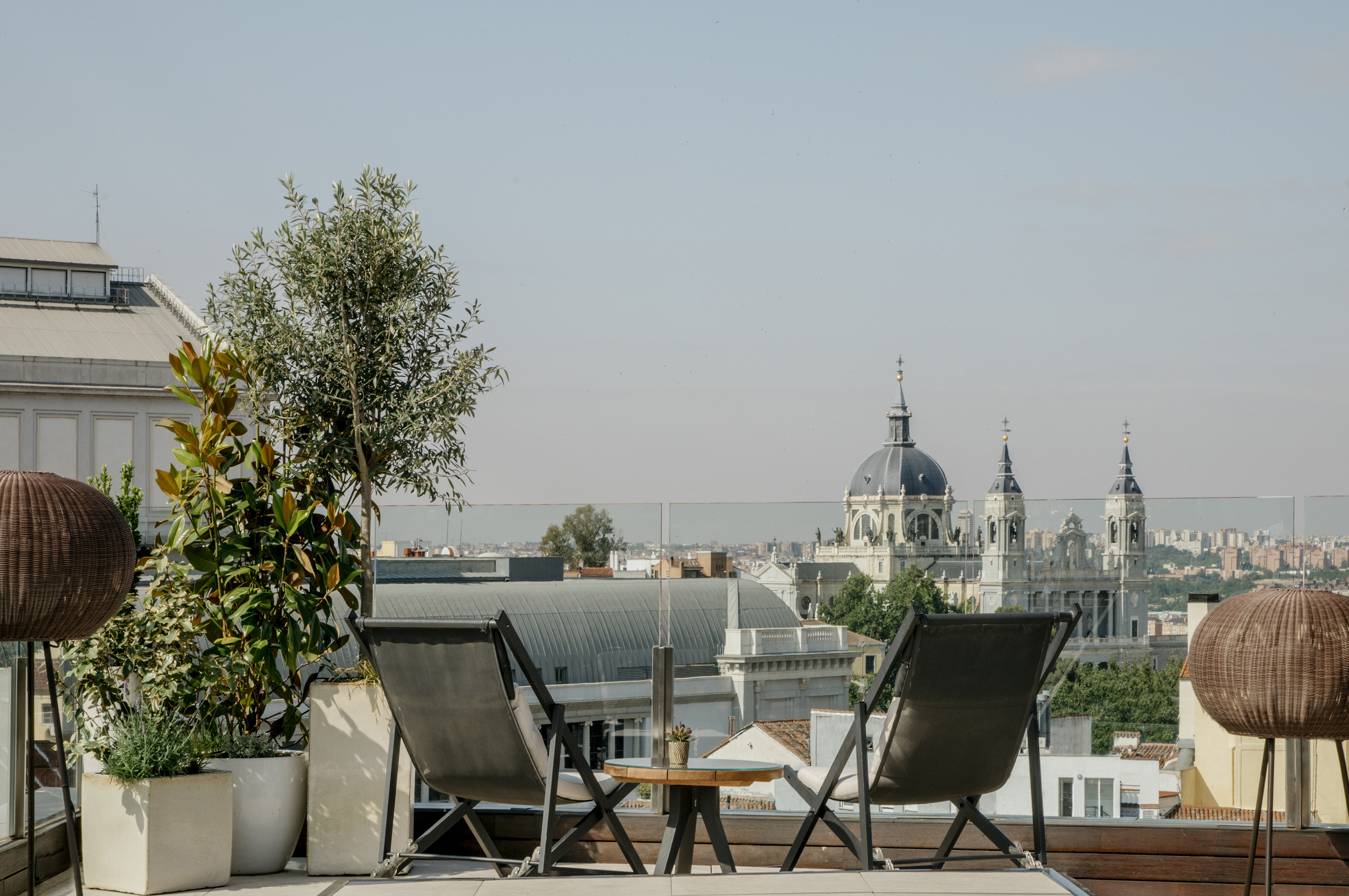 Madrid rooftop terrace with chairs, plants, and Almudena Cathedral view.