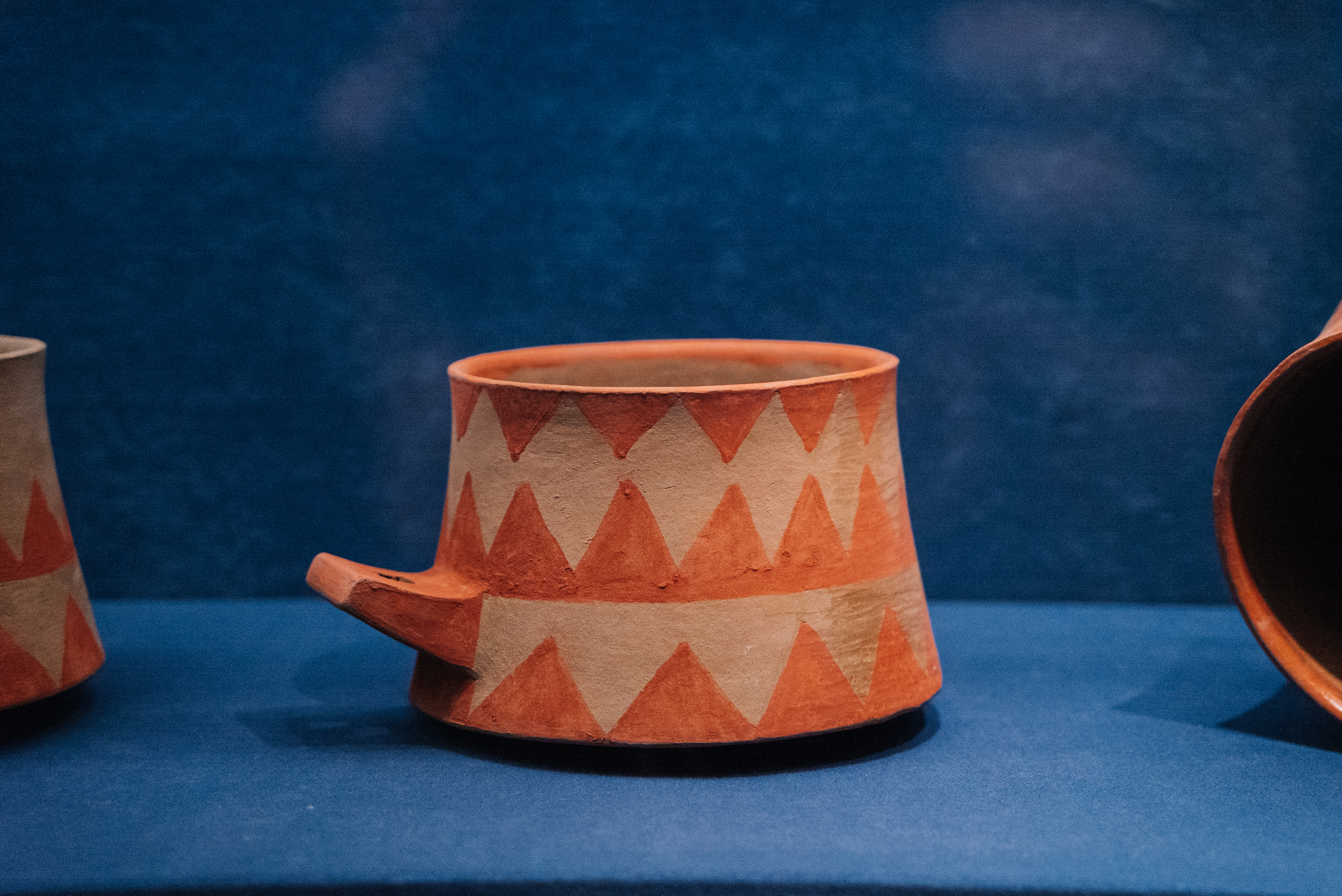 Terracotta ceramic pot with geometric triangular pattern and small spout.