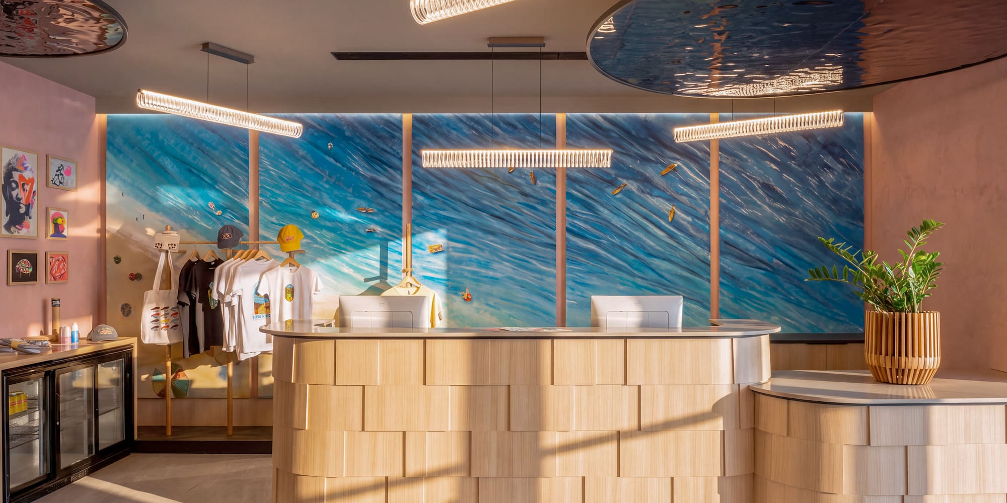 Coastal-themed hotel reception with wood desk, ocean mural, and boutique display.