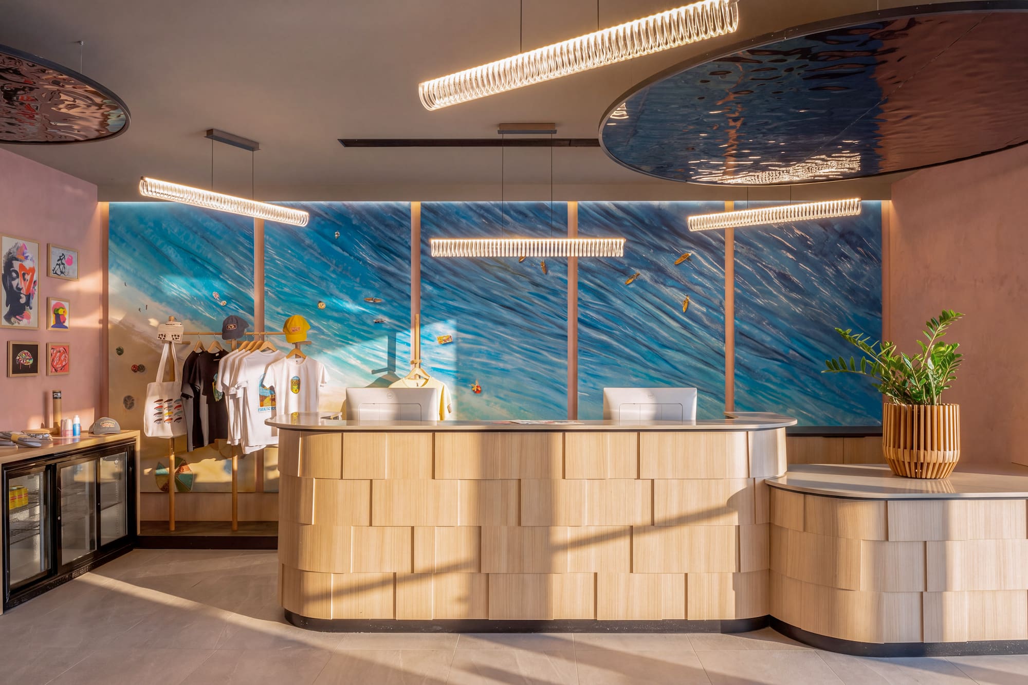 Coastal-themed hotel reception with wood desk, ocean mural, and boutique display.
