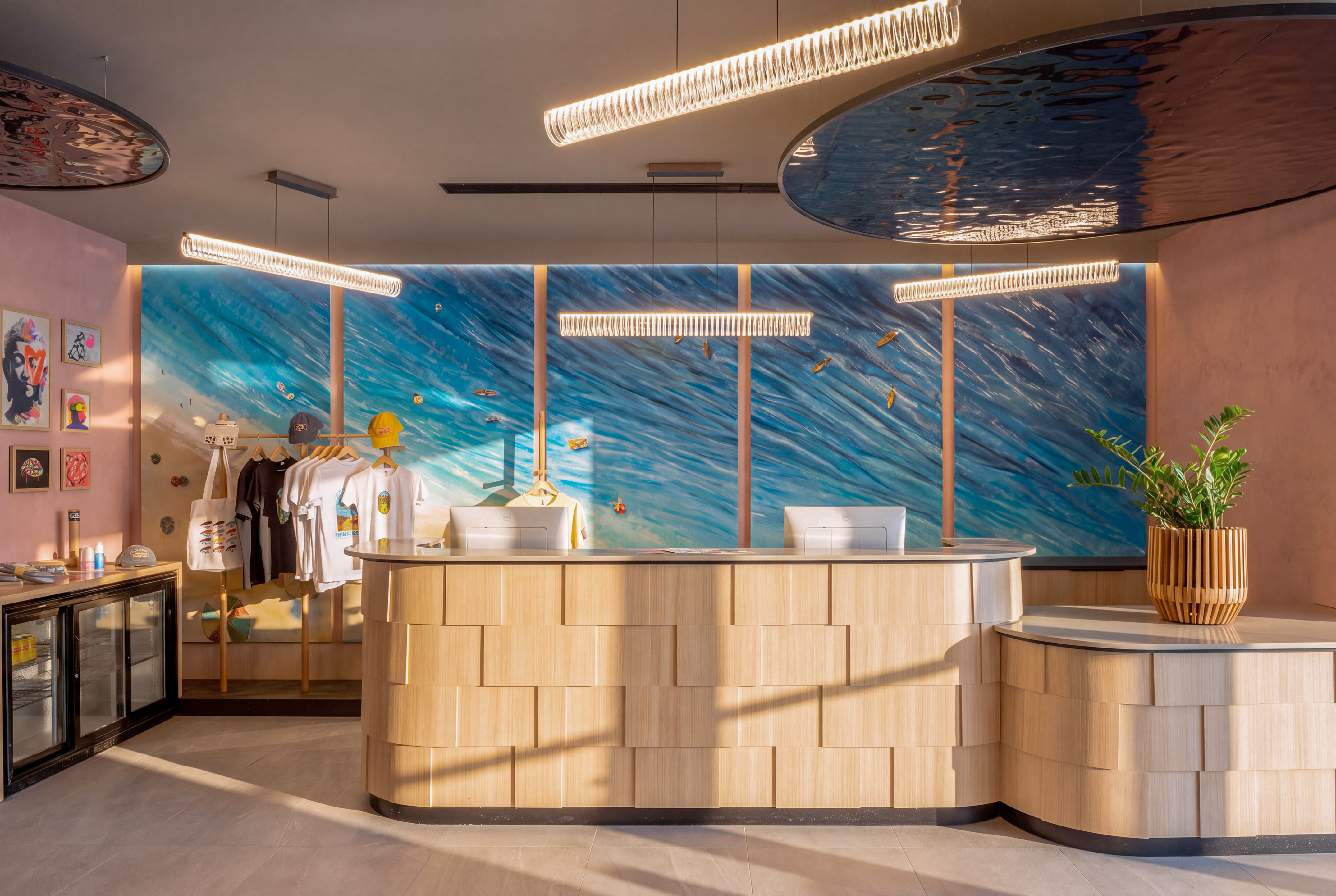 Coastal-themed hotel reception with wood desk, ocean mural, and boutique display.