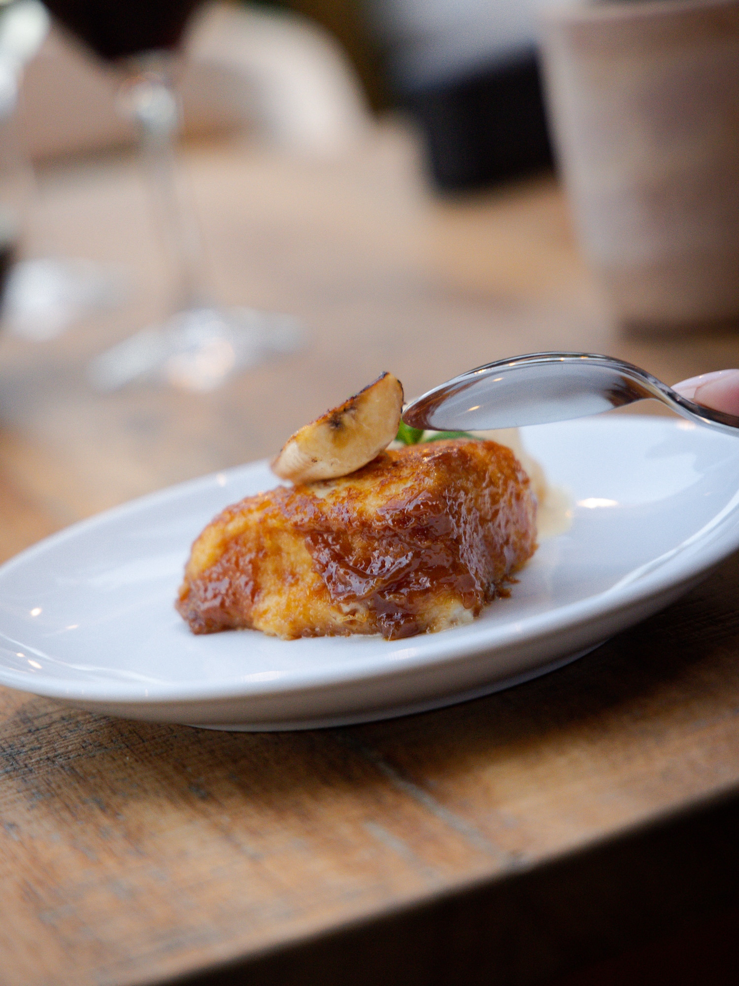 a person holding a spoon over a piece of food on a plate