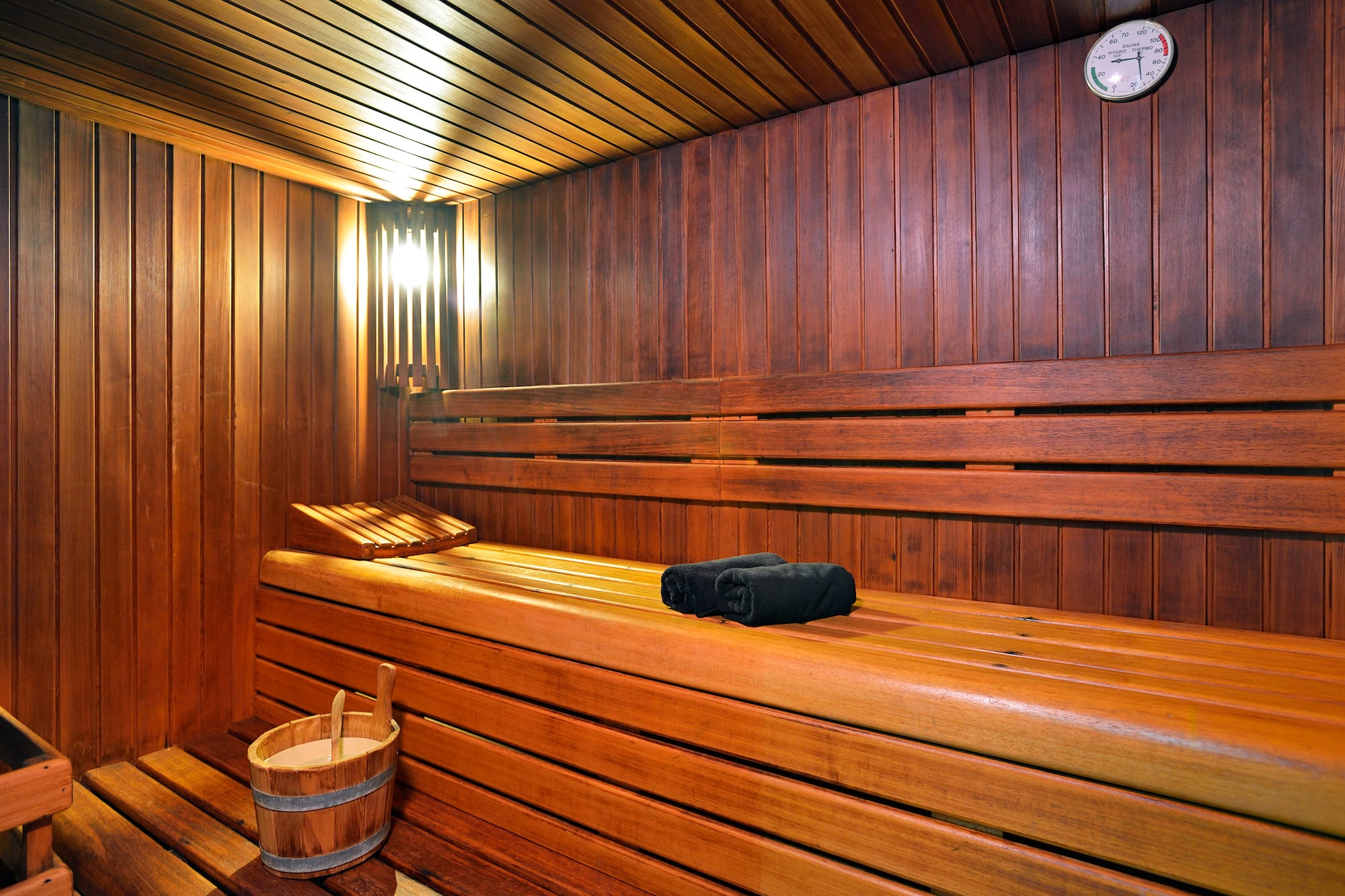 a wooden sauna with a bucket and a towel