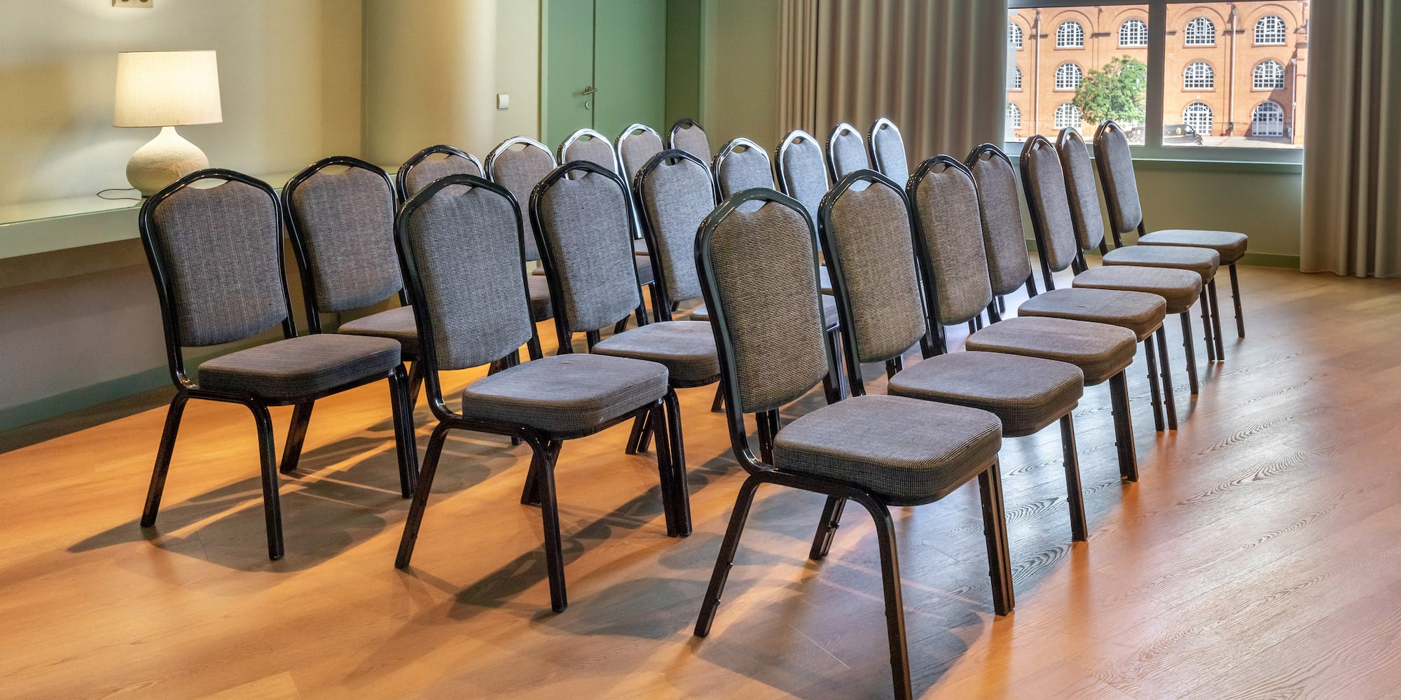 Business conference room with gray chairs, polished wood floor, and window.