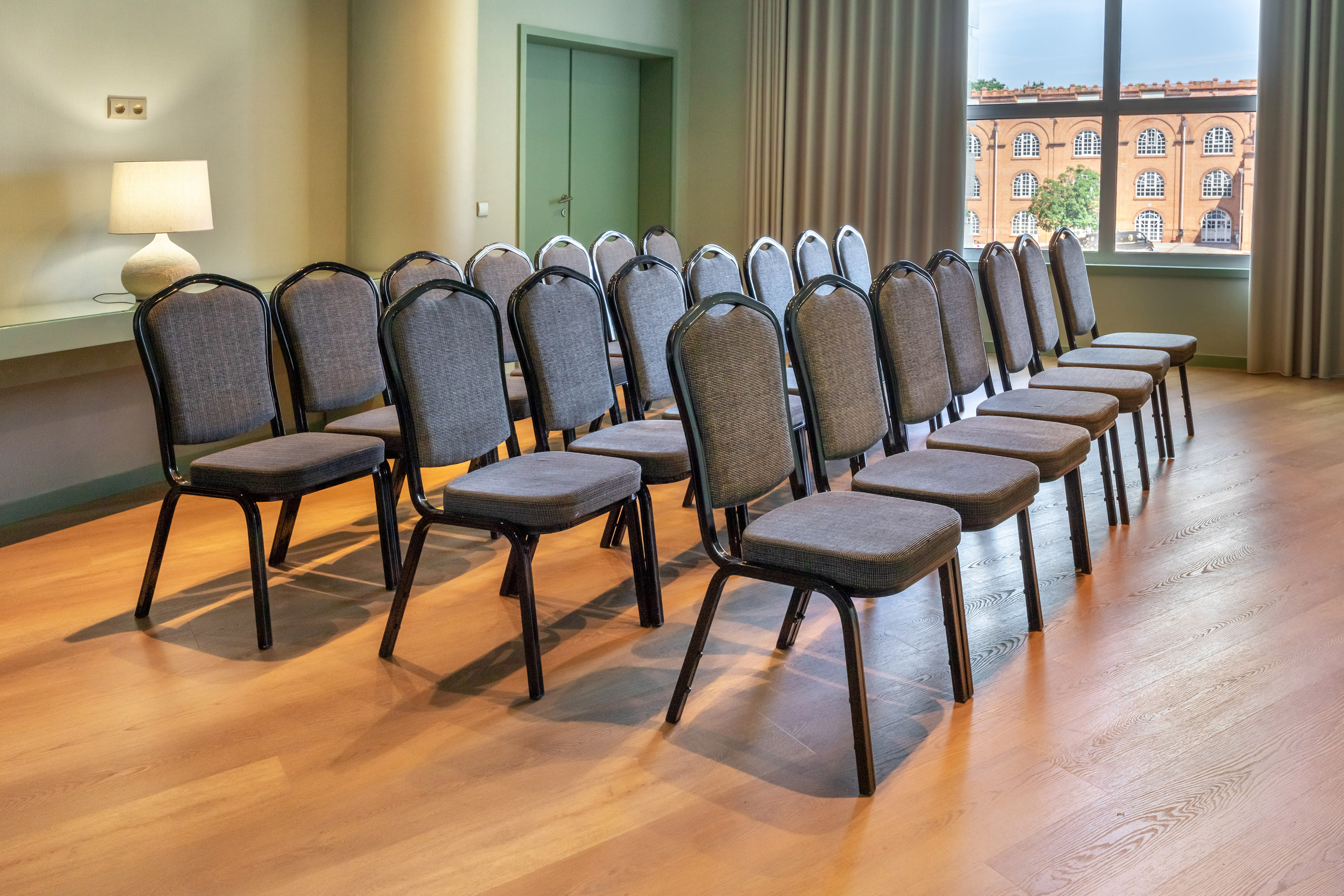 Business conference room with gray chairs, polished wood floor, and window.