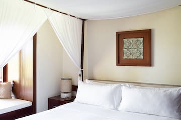 a bed with white sheets and a white curtain above it