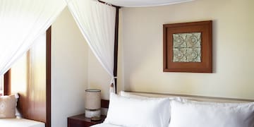 a bed with white sheets and a white curtain above it