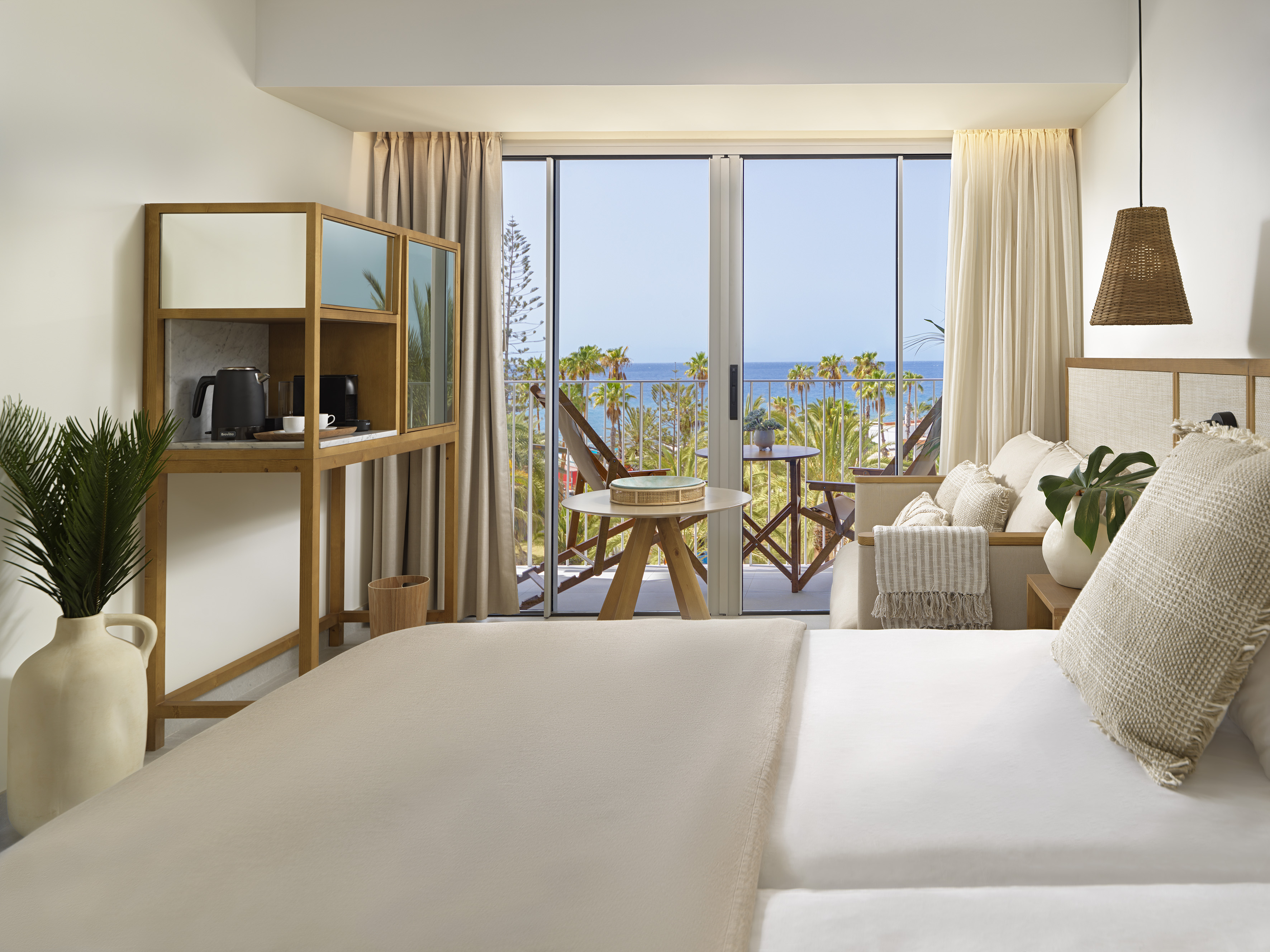 Coastal hotel room with balcony, ocean view, and modern wood furnishings.
