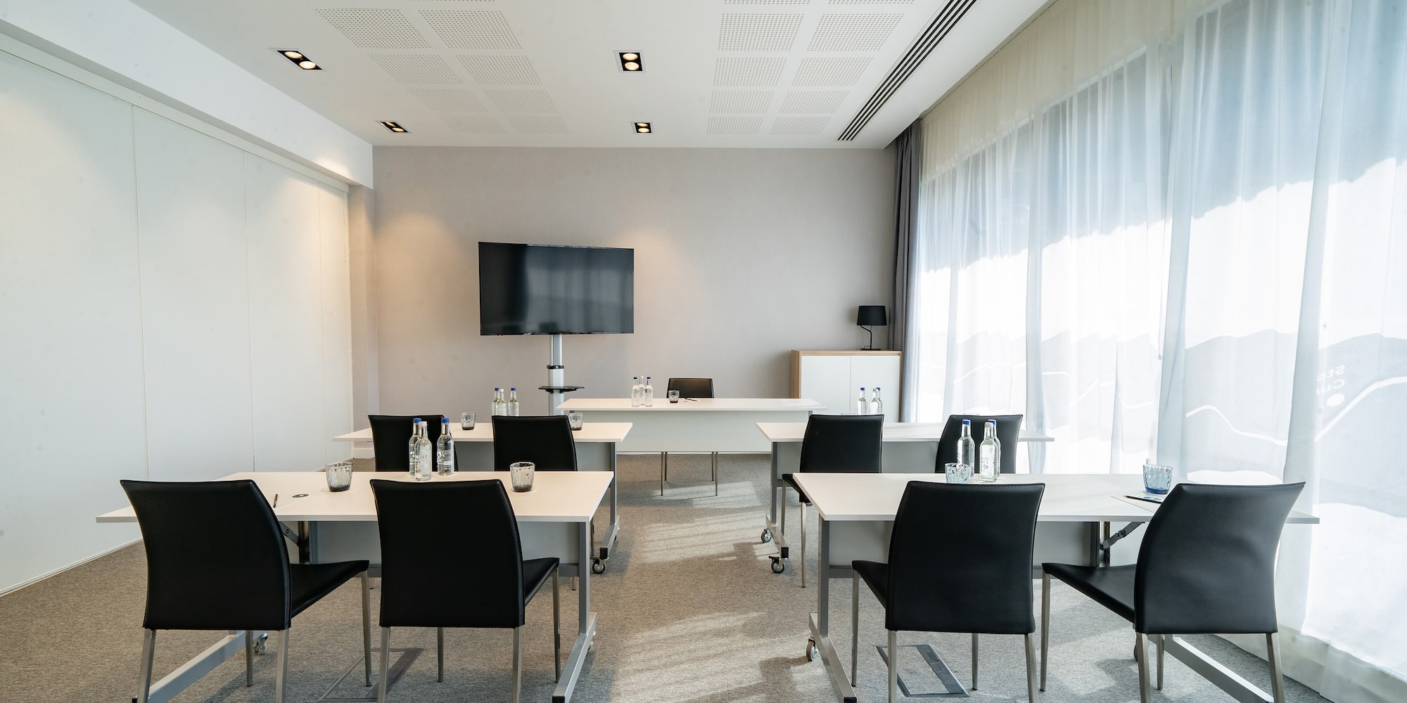 a room with white tables and black chairs
