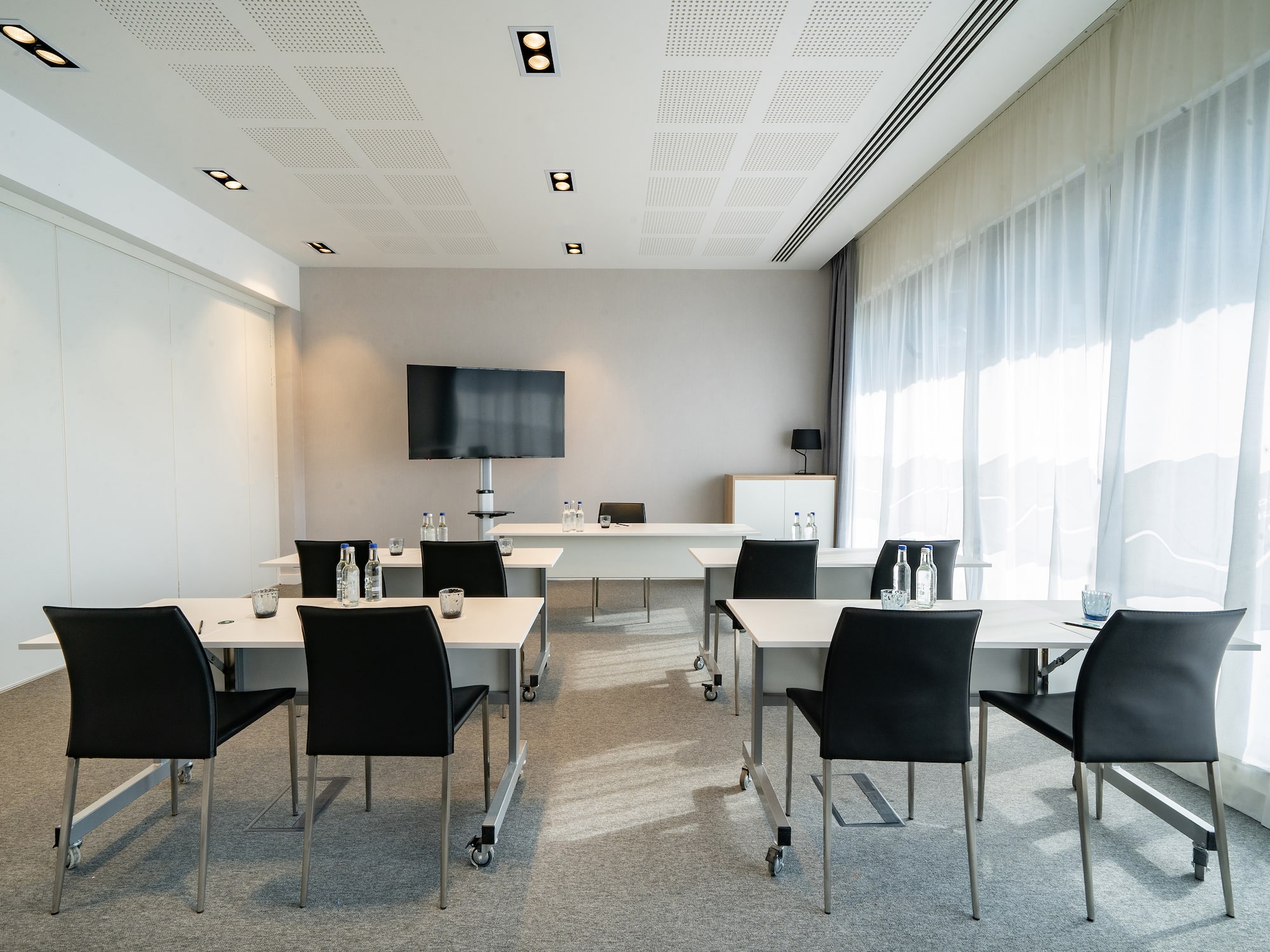 a room with white tables and black chairs