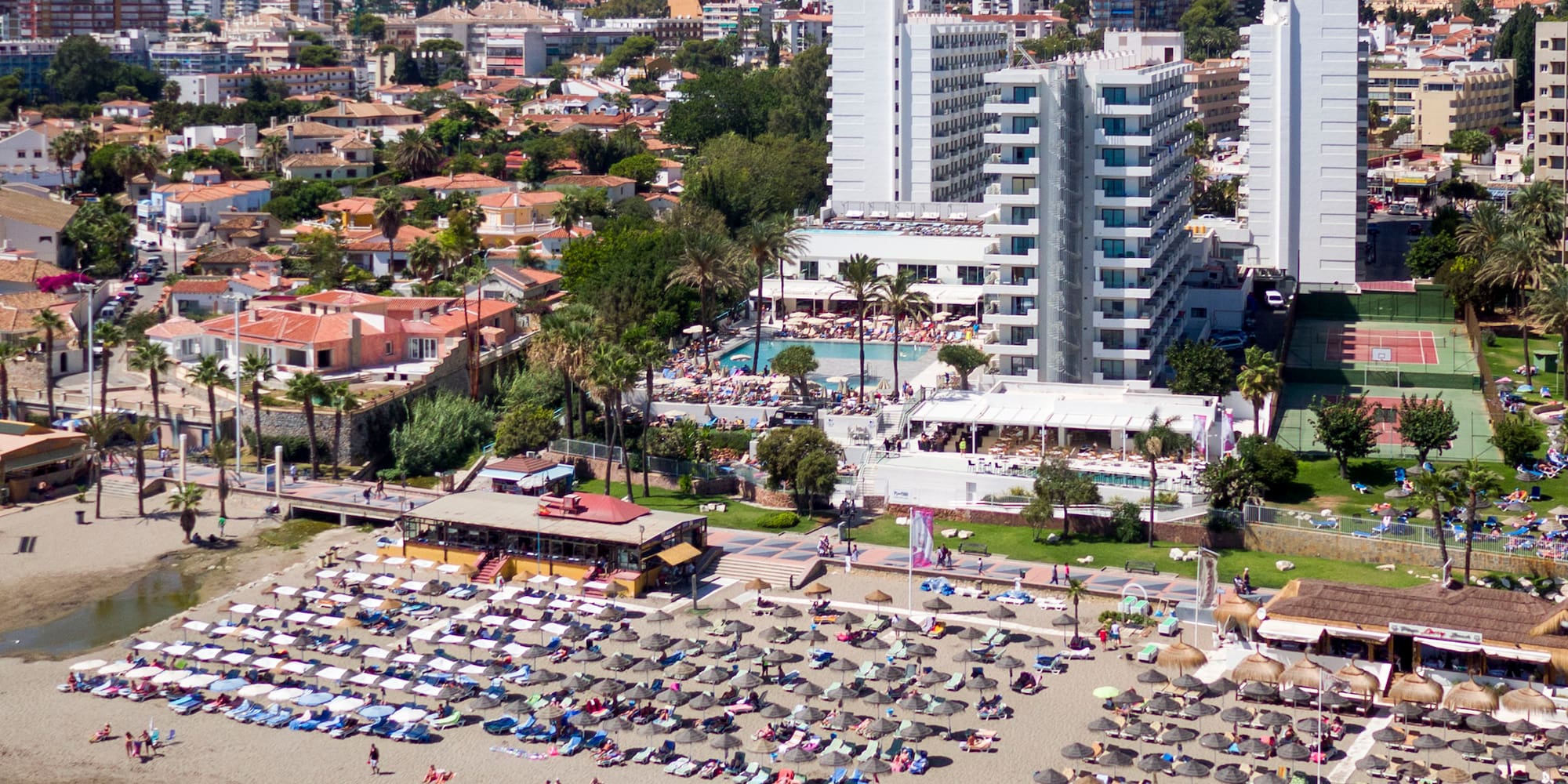 a beach with many chairs and umbrellas and buildings