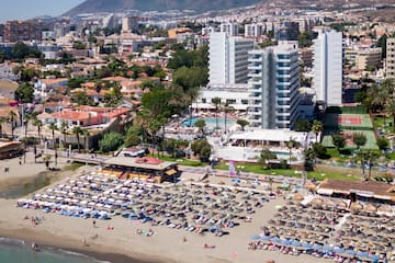 a beach with many chairs and umbrellas and buildings