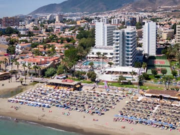 a beach with many chairs and umbrellas and buildings