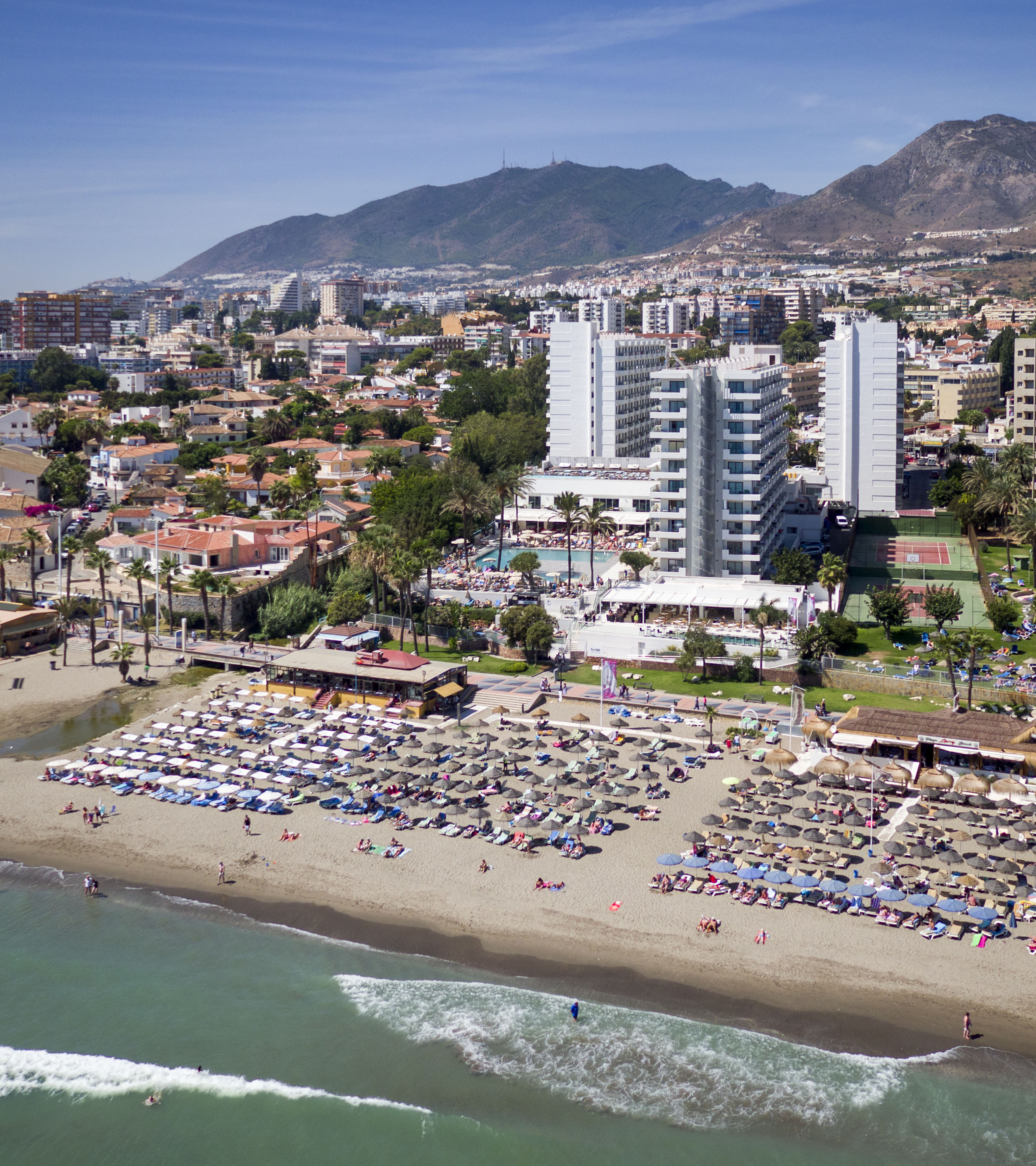 a beach with many chairs and umbrellas and buildings