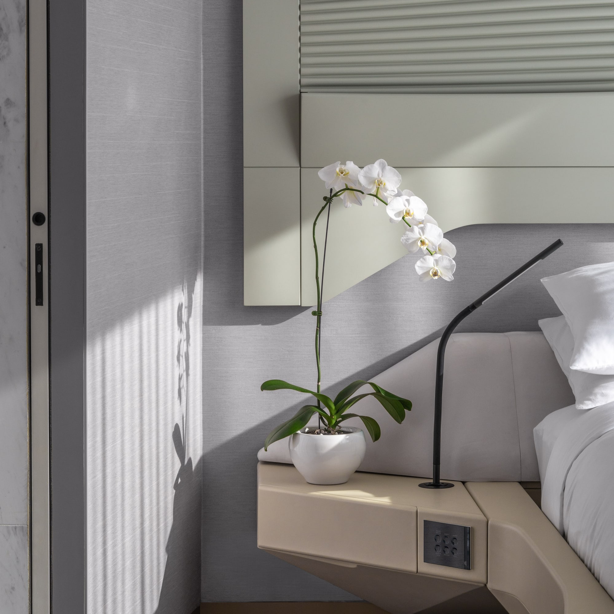 a plant on a table next to a bed.