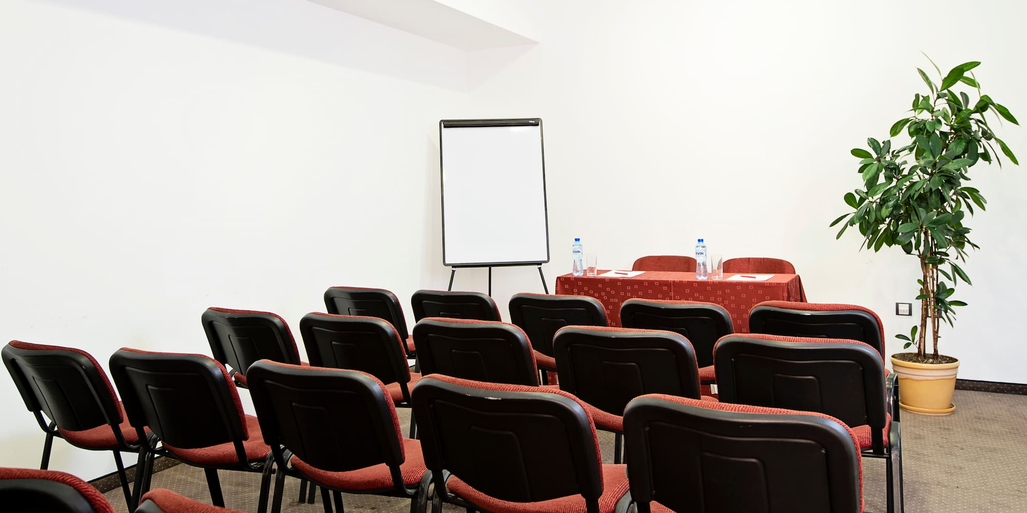a room with red chairs and a white board