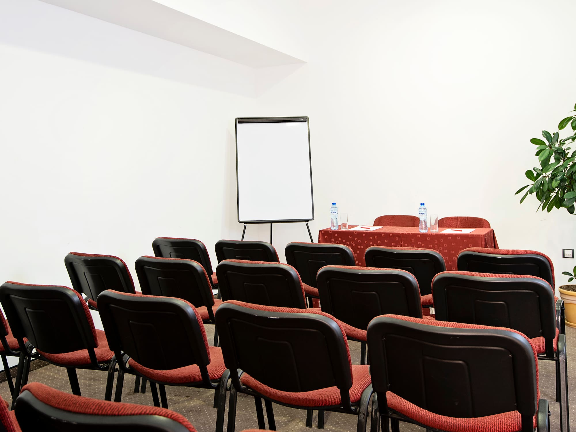 a room with red chairs and a white board