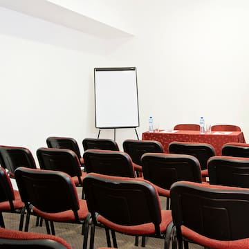 a room with red chairs and a white board
