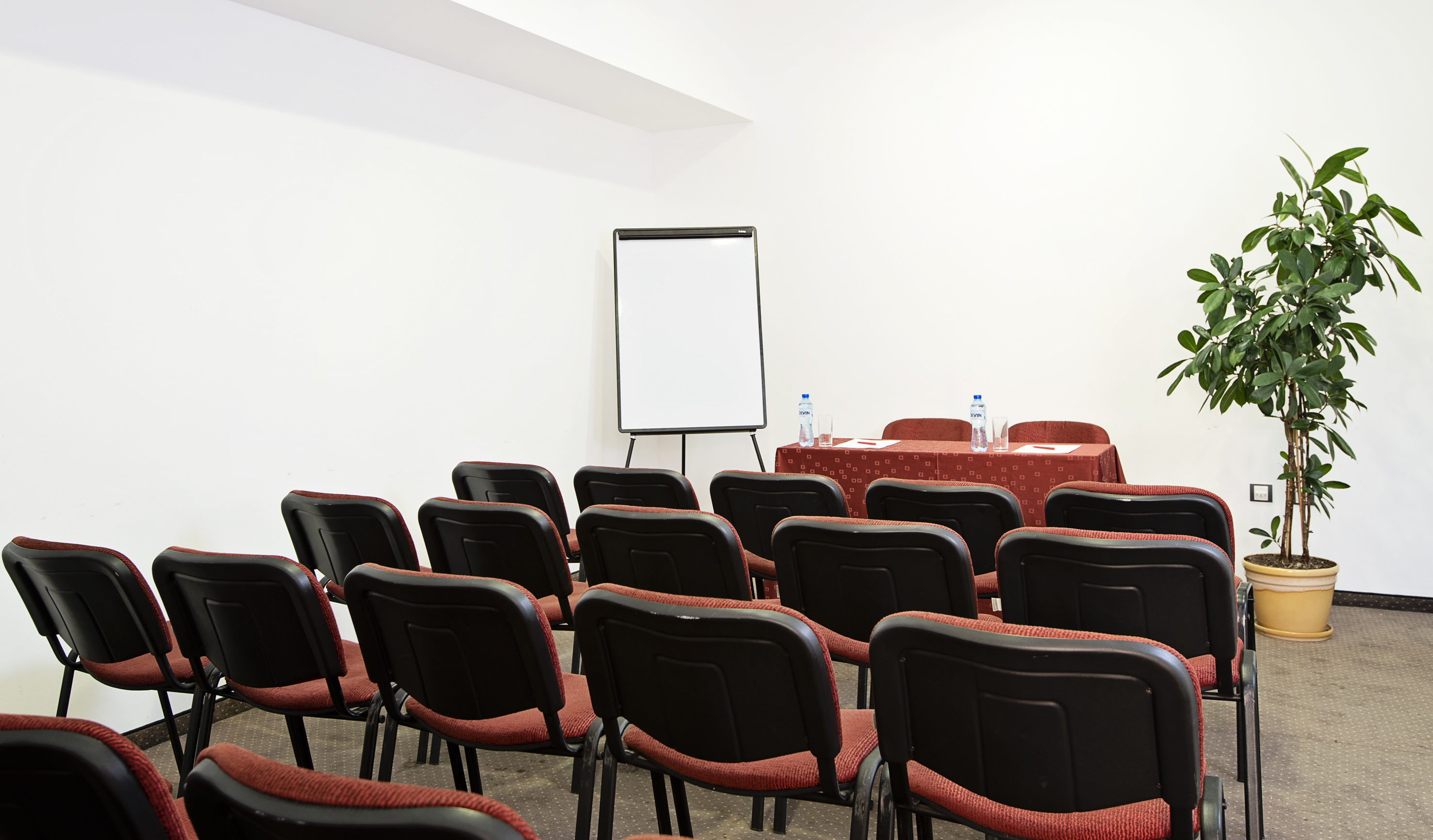 a room with red chairs and a white board