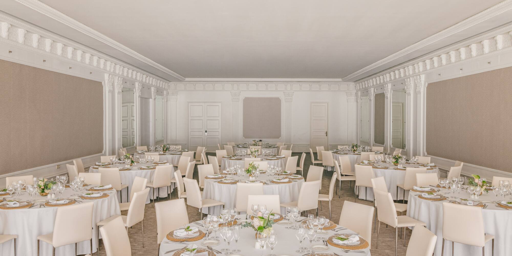 Elegant banquet hall with round dining tables, white linens, and chairs.