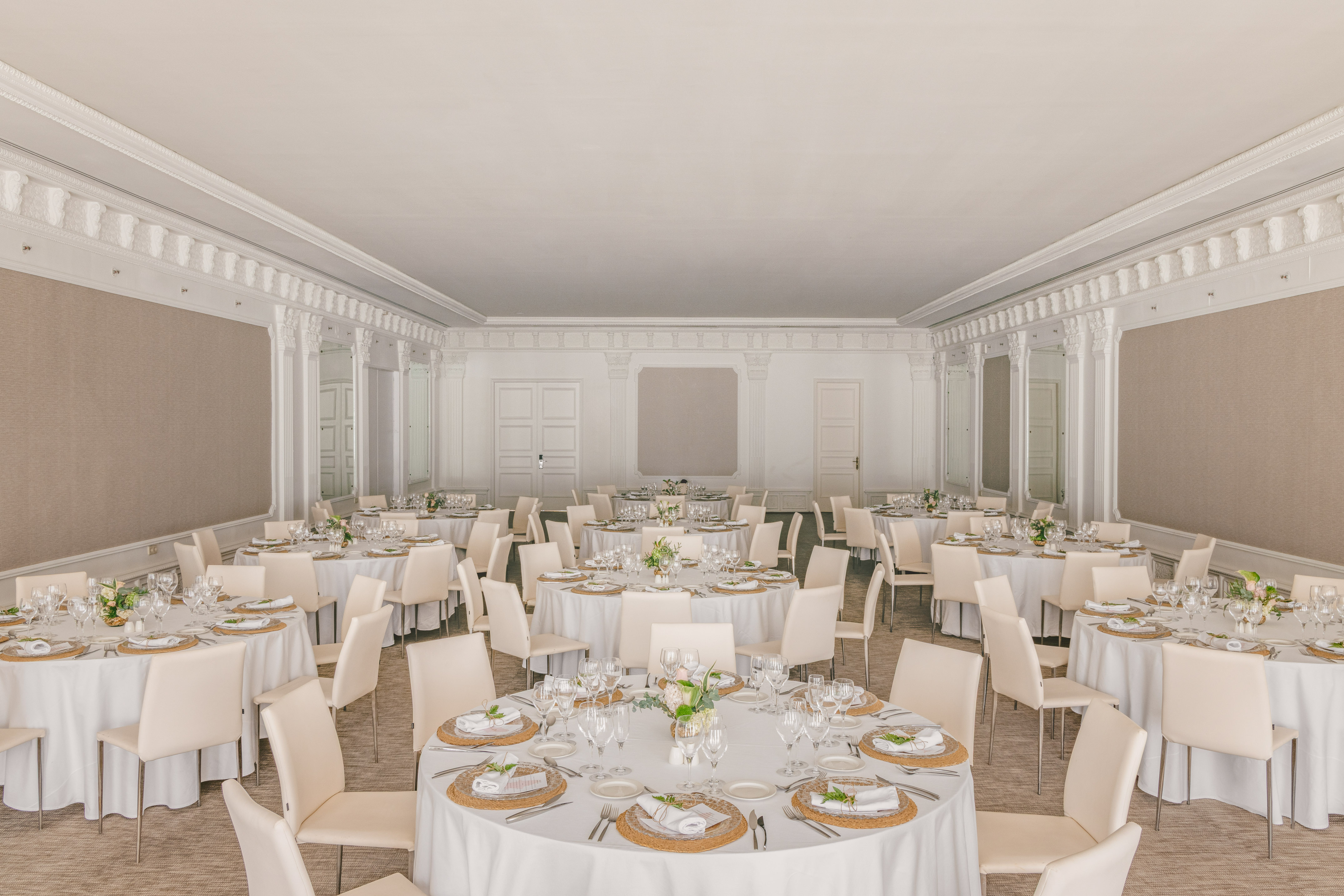 Elegant banquet hall with round dining tables, white linens, and chairs.