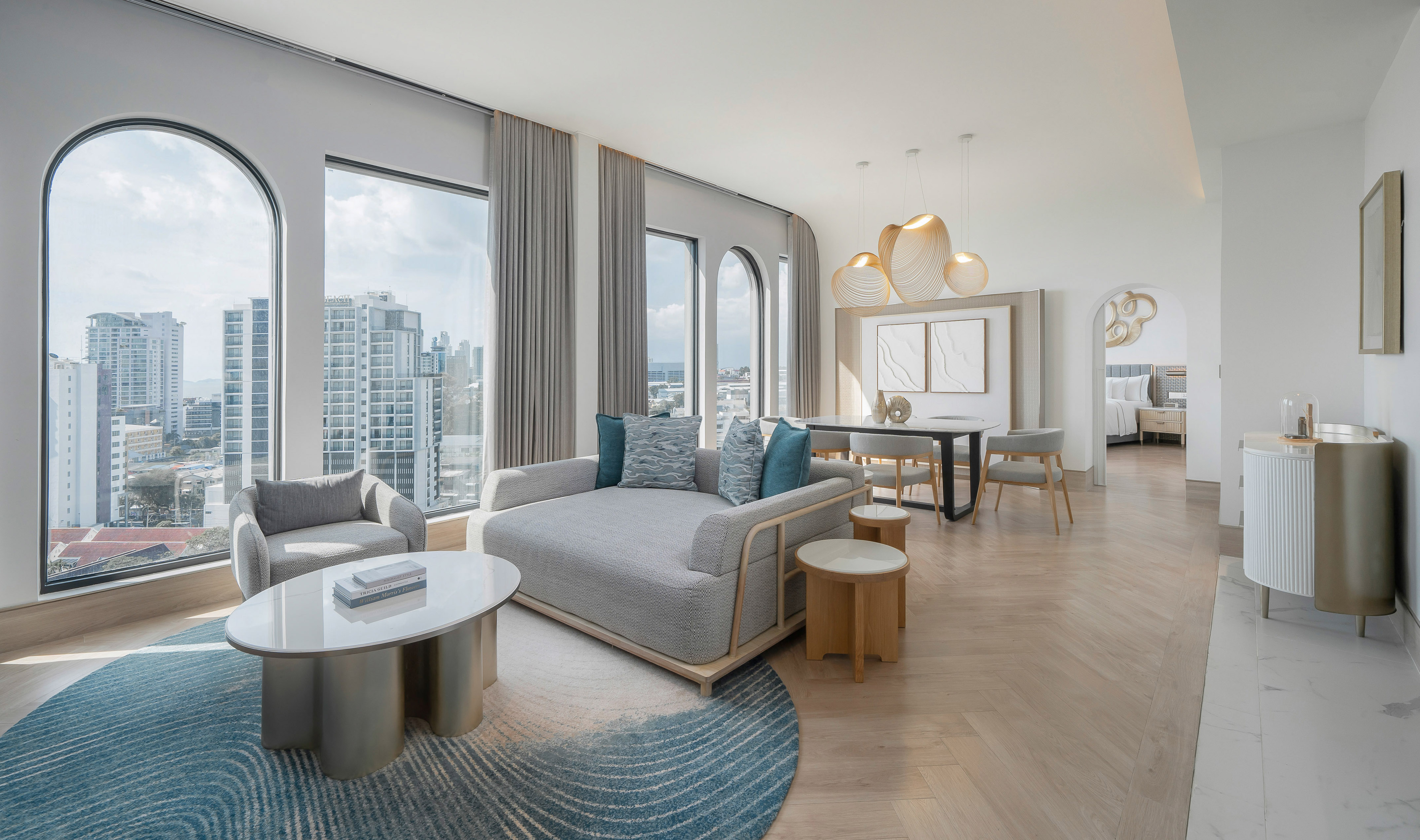 Luxury modern living room with city view, sofa, dining, and bedroom access.
