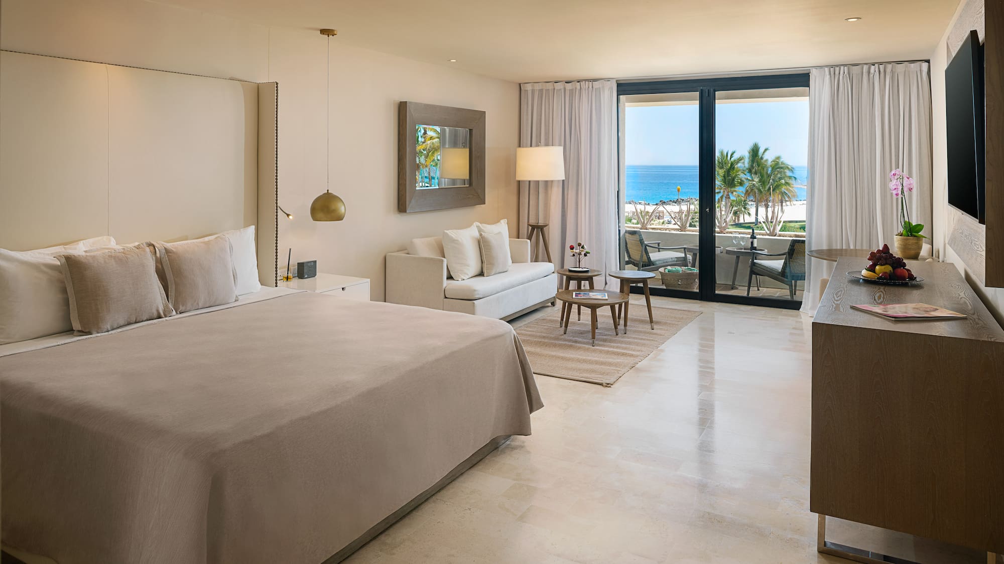 Luxury hotel room with ocean view balcony, king bed, and modern decor.