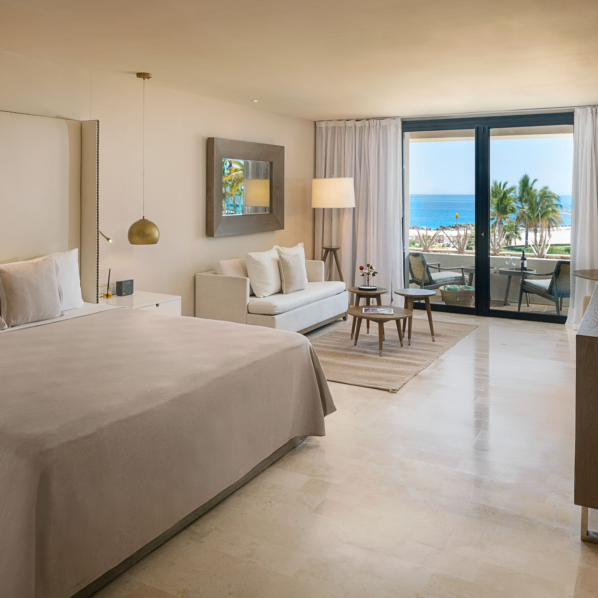 Luxury hotel room with ocean view balcony, king bed, and modern decor.