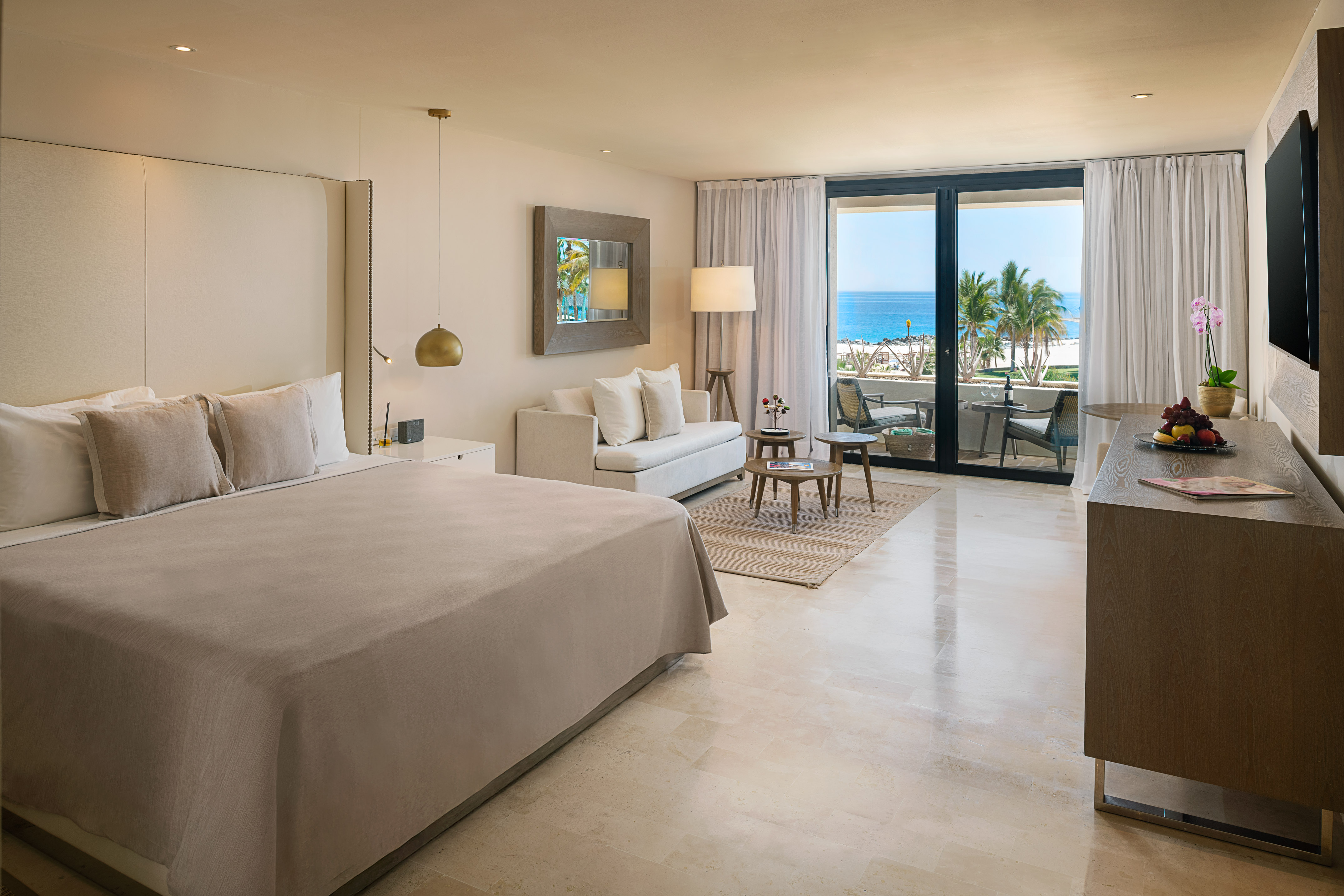 Luxury hotel room with ocean view balcony, king bed, and modern decor.