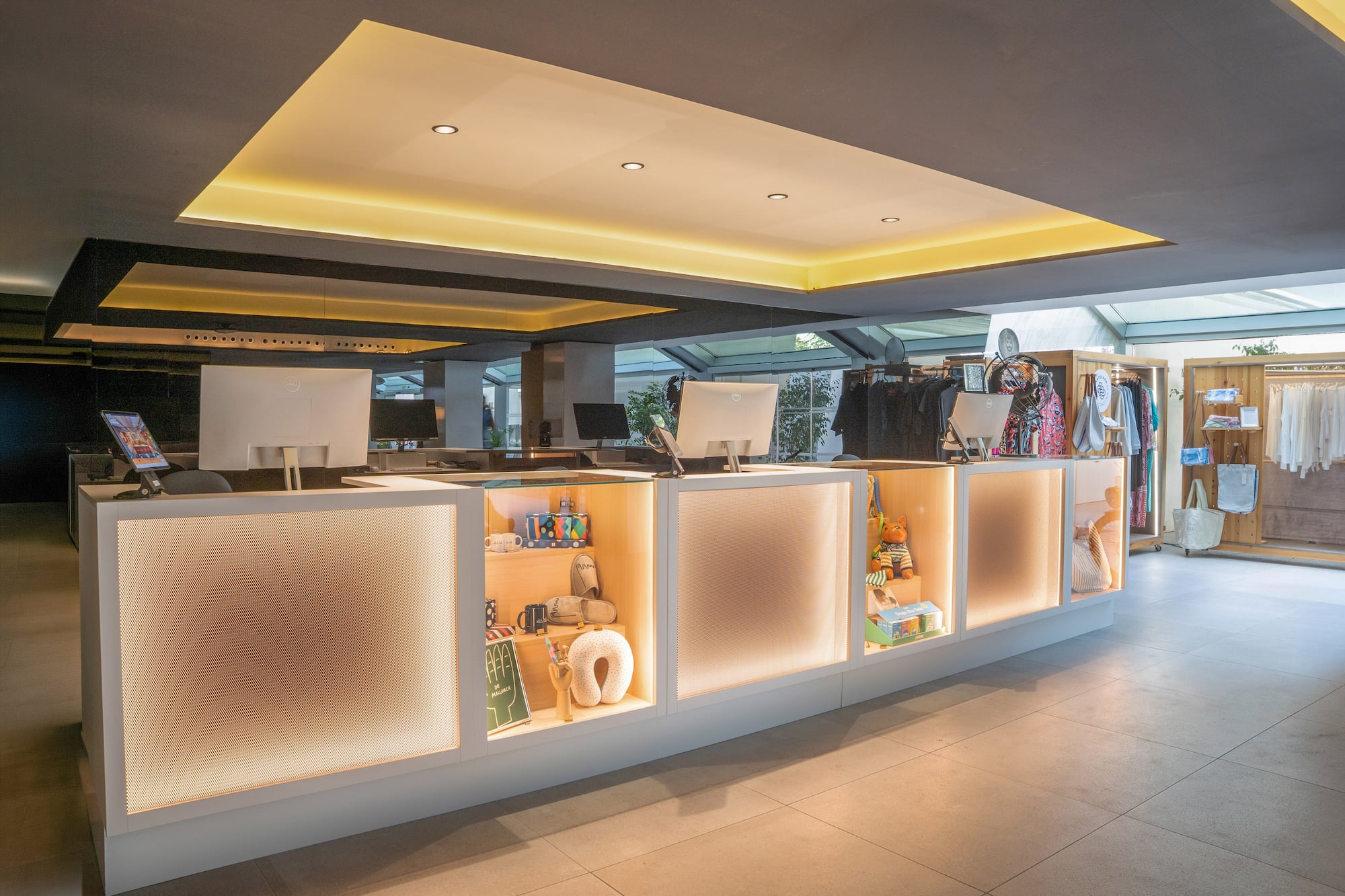 Illuminated reception and retail counter with merchandise display in modern lobby.