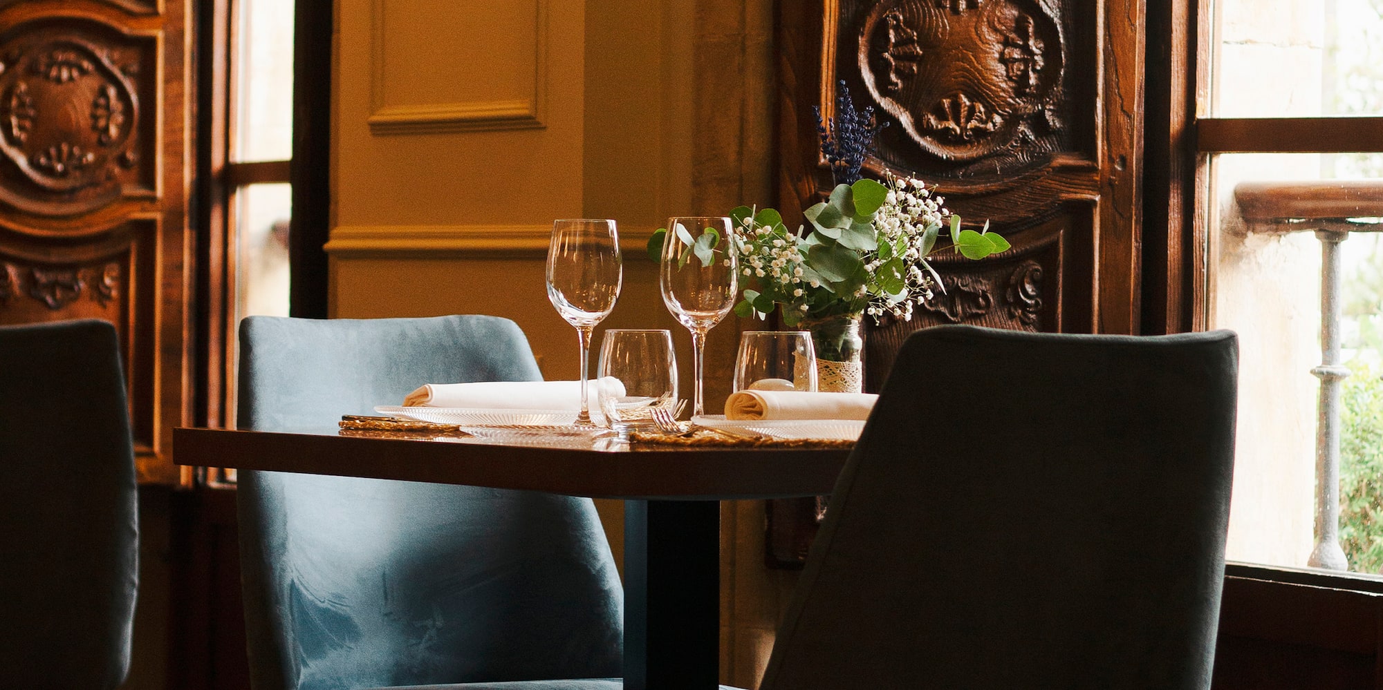 a table with wine glasses and chairs in a room with a window
