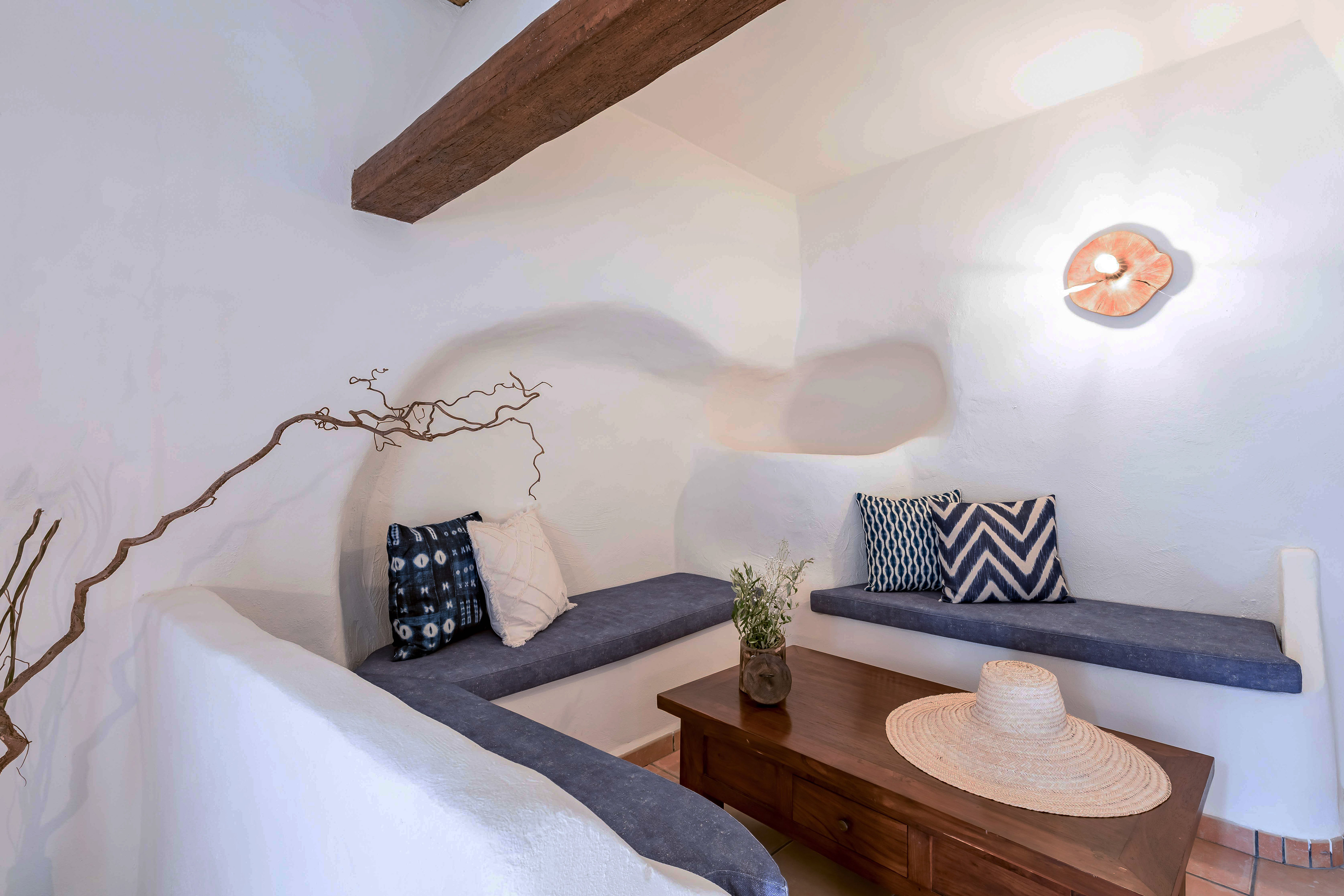 Mediterranean lounge with white walls, built-in blue seating, wooden table.