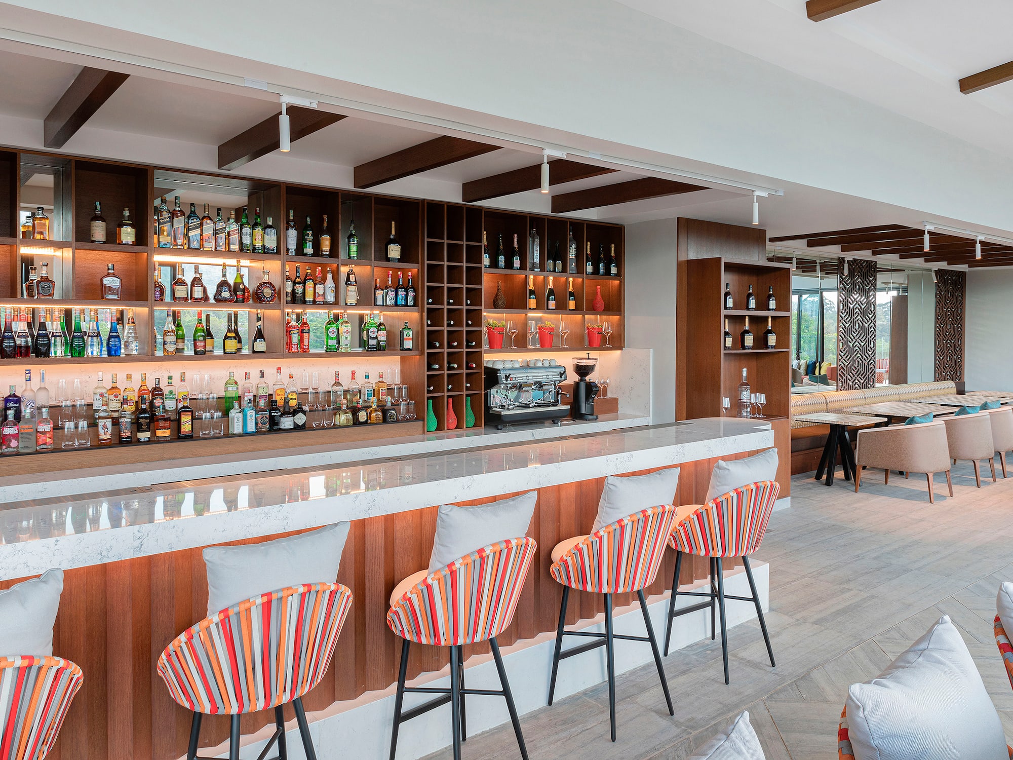 a bar with shelves of liquor and chairs