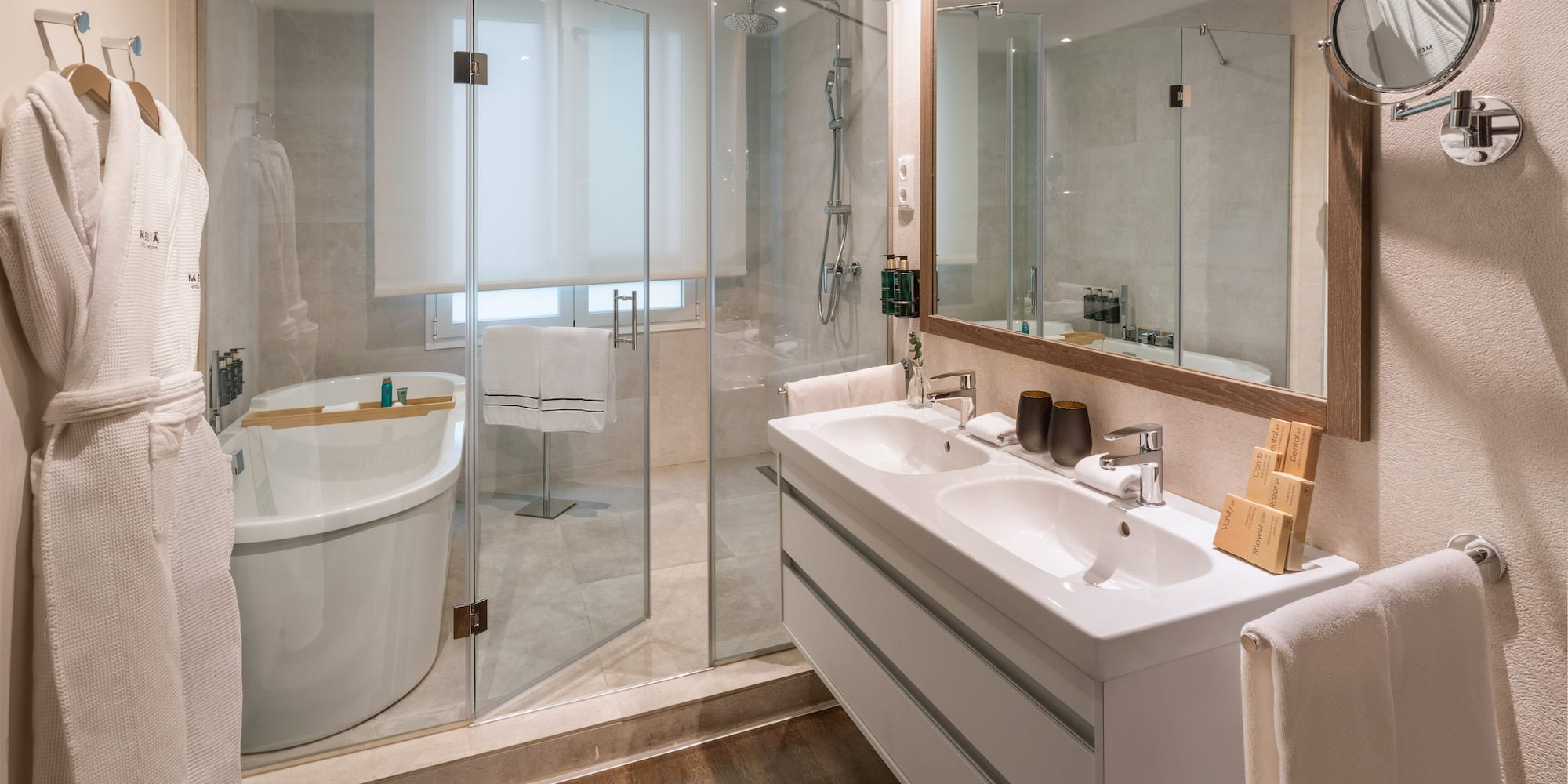 Modern hotel bathroom with freestanding tub, glass shower, and double vanity.