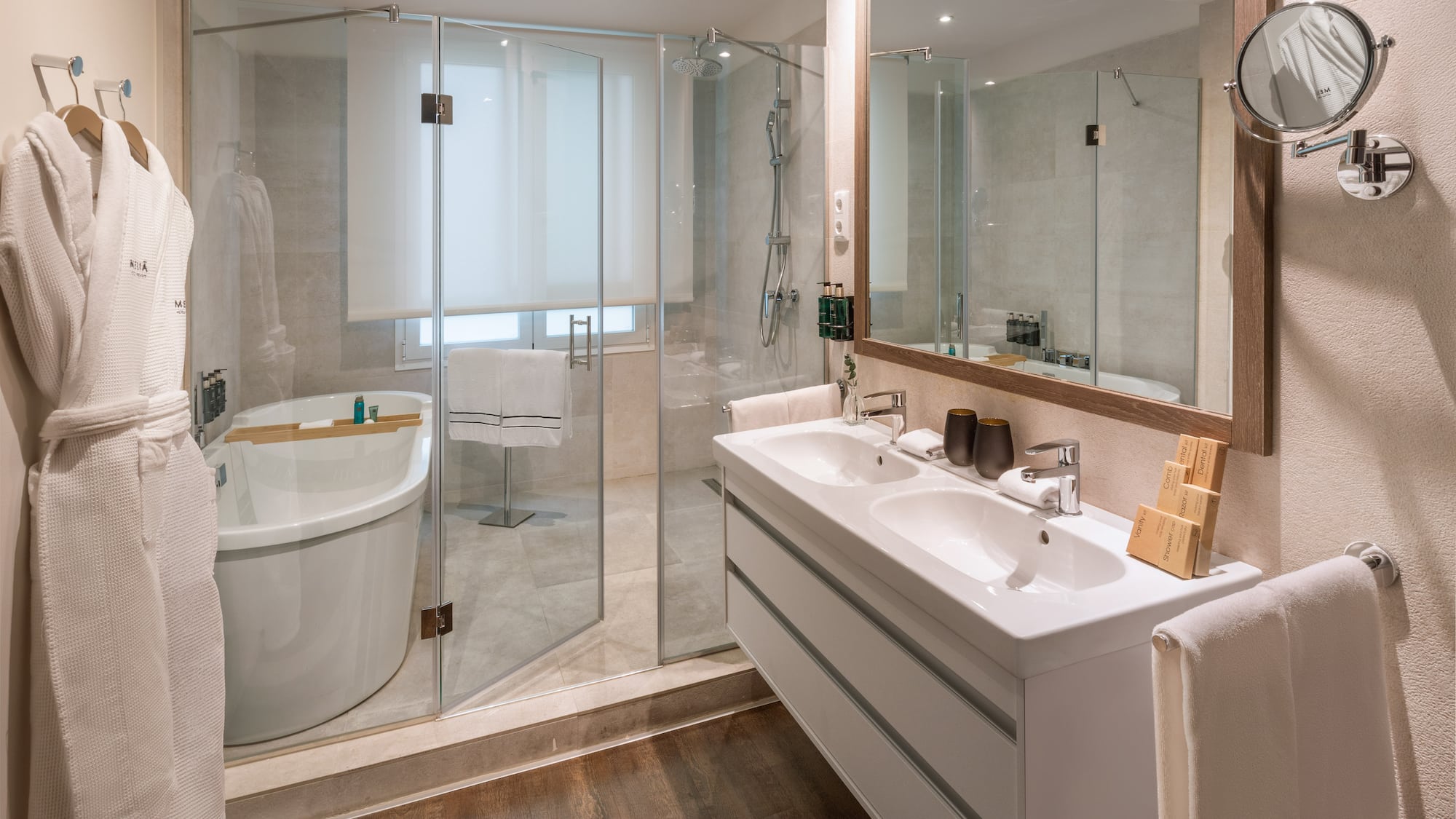 Modern bathroom: glass shower, freestanding tub, double vanity, wooden floor.