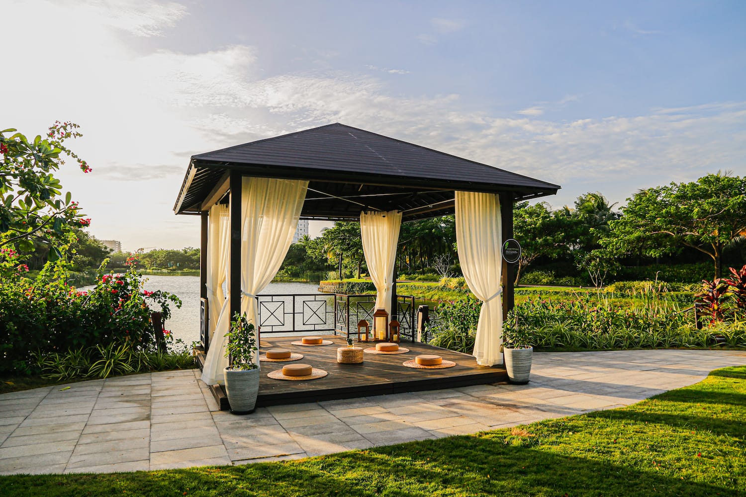 a gazebo with white curtains and a lake in the background