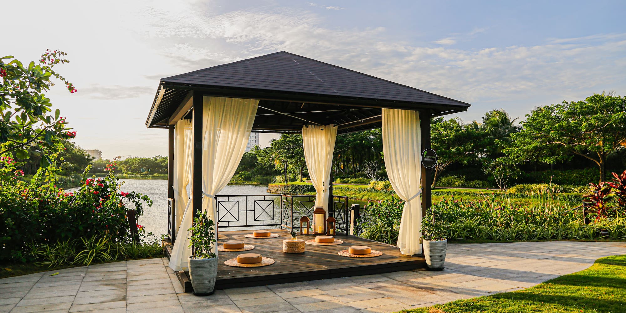 a gazebo with white curtains and a lake in the background