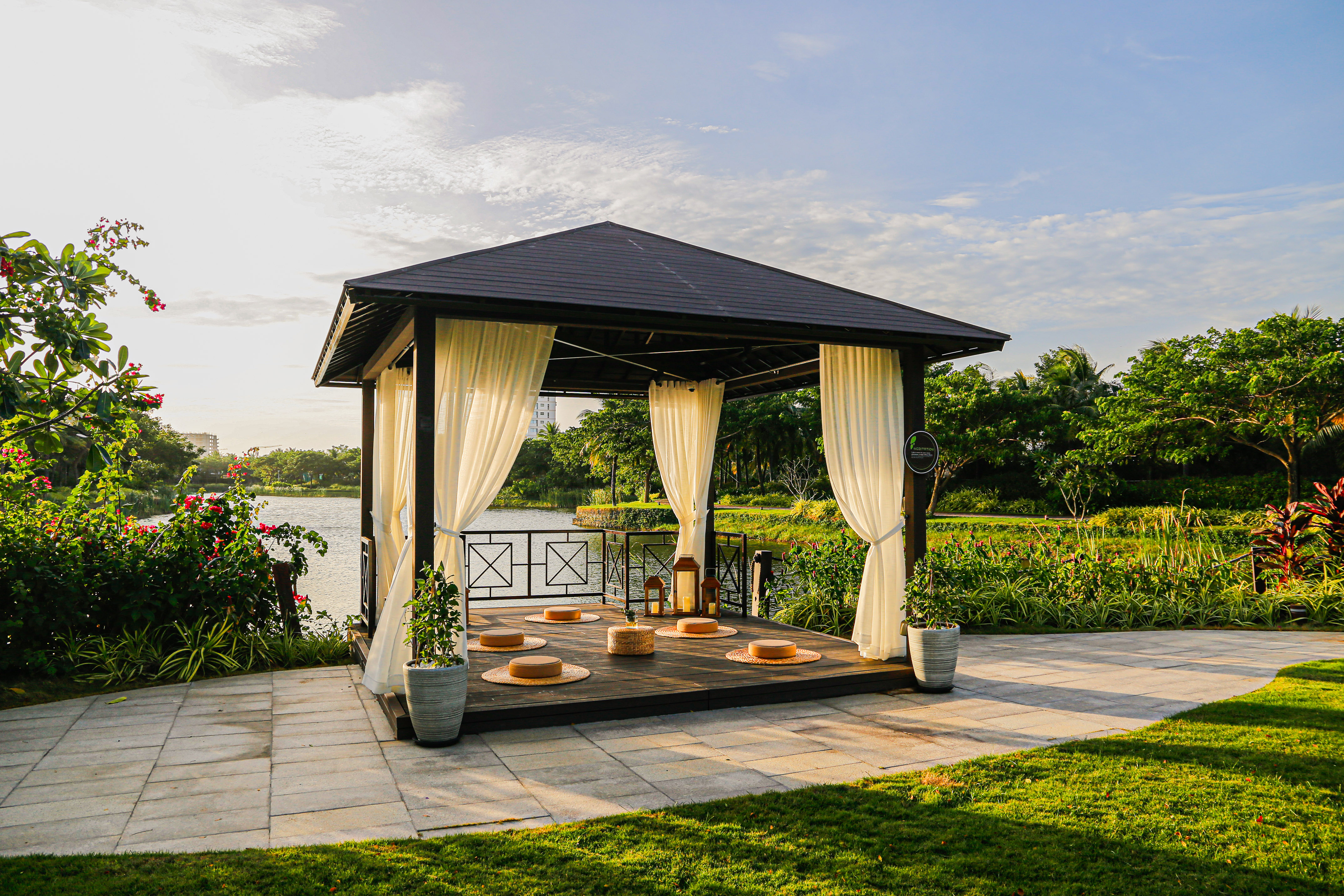 a gazebo with white curtains and a lake in the background