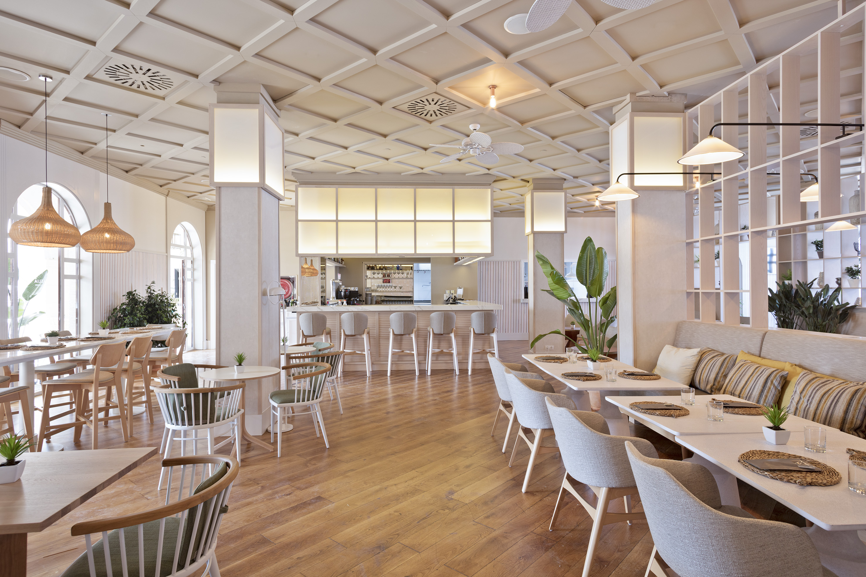 Modern bright restaurant interior with dining tables, bar, and wood floor.