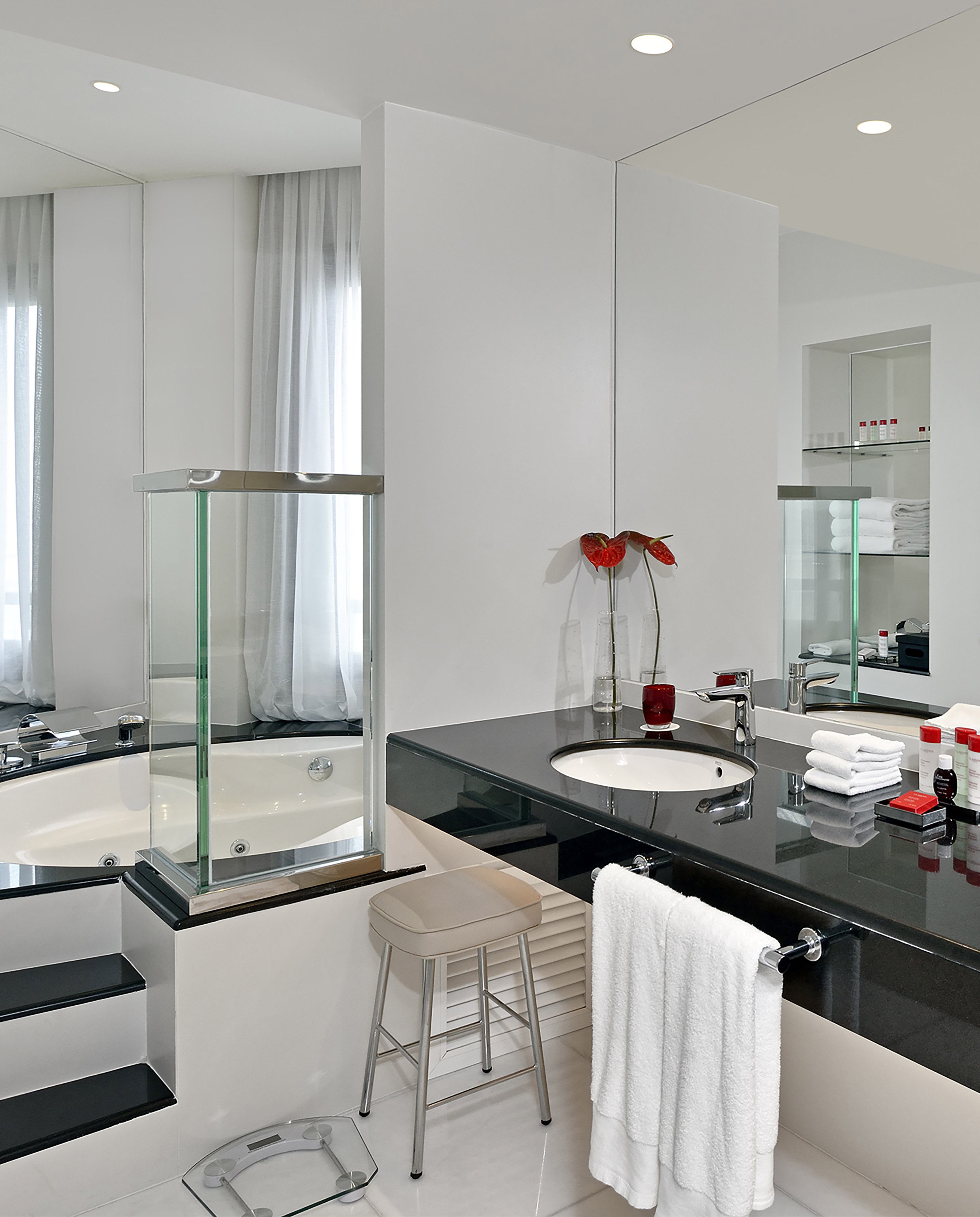 Modern black and white bathroom with large tub, glass divider, and vanity sink.