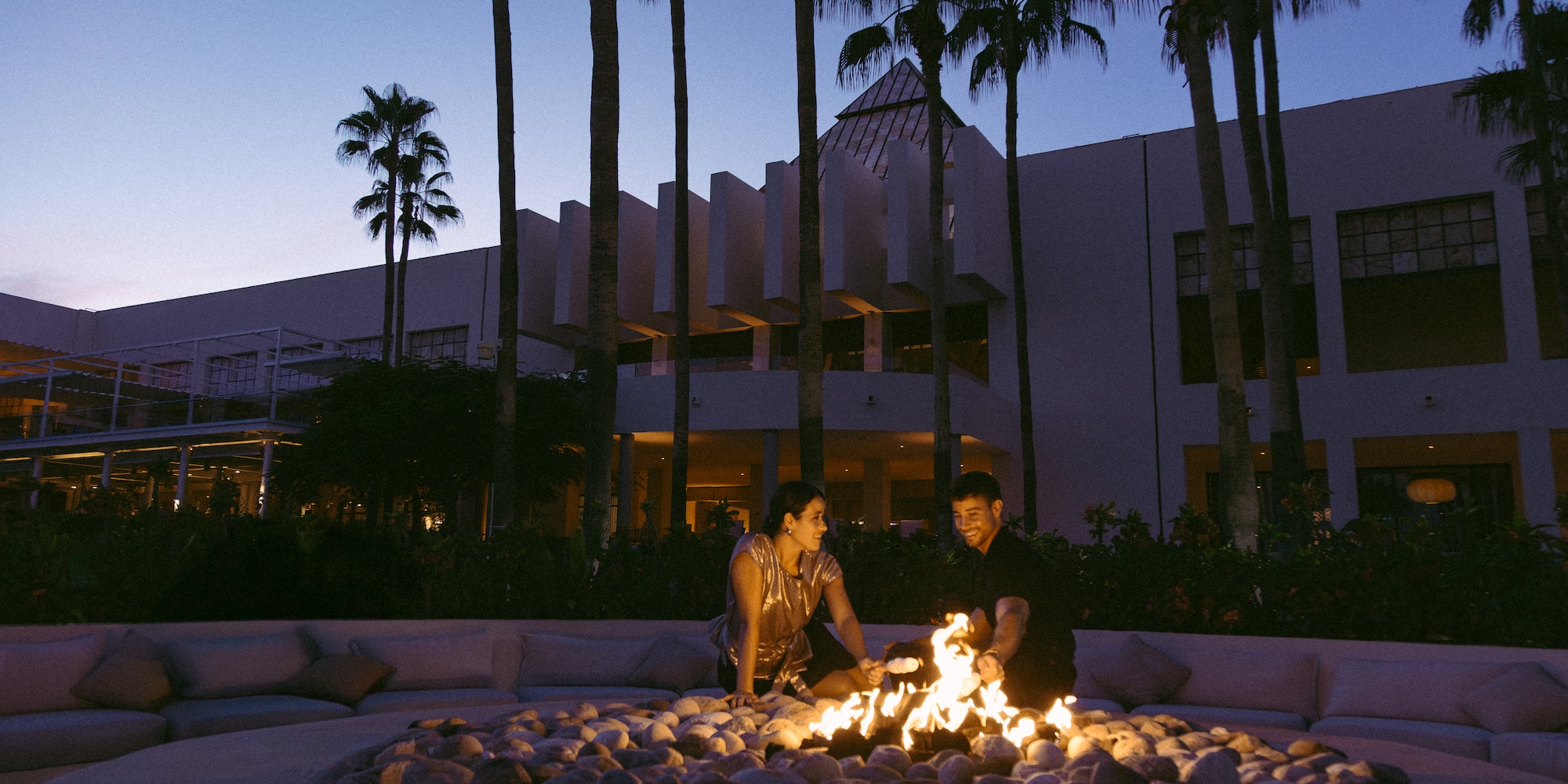 a man and woman standing around a fire pit