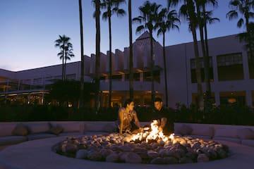 a man and woman standing around a fire pit