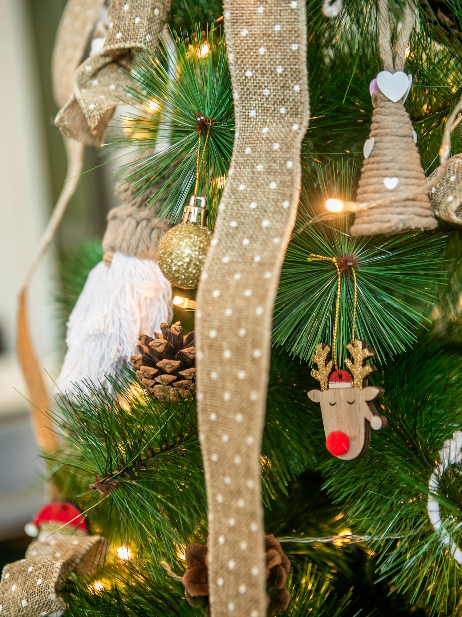 Festive Christmas tree with rustic reindeer, pinecones, burlap, and warm lights.