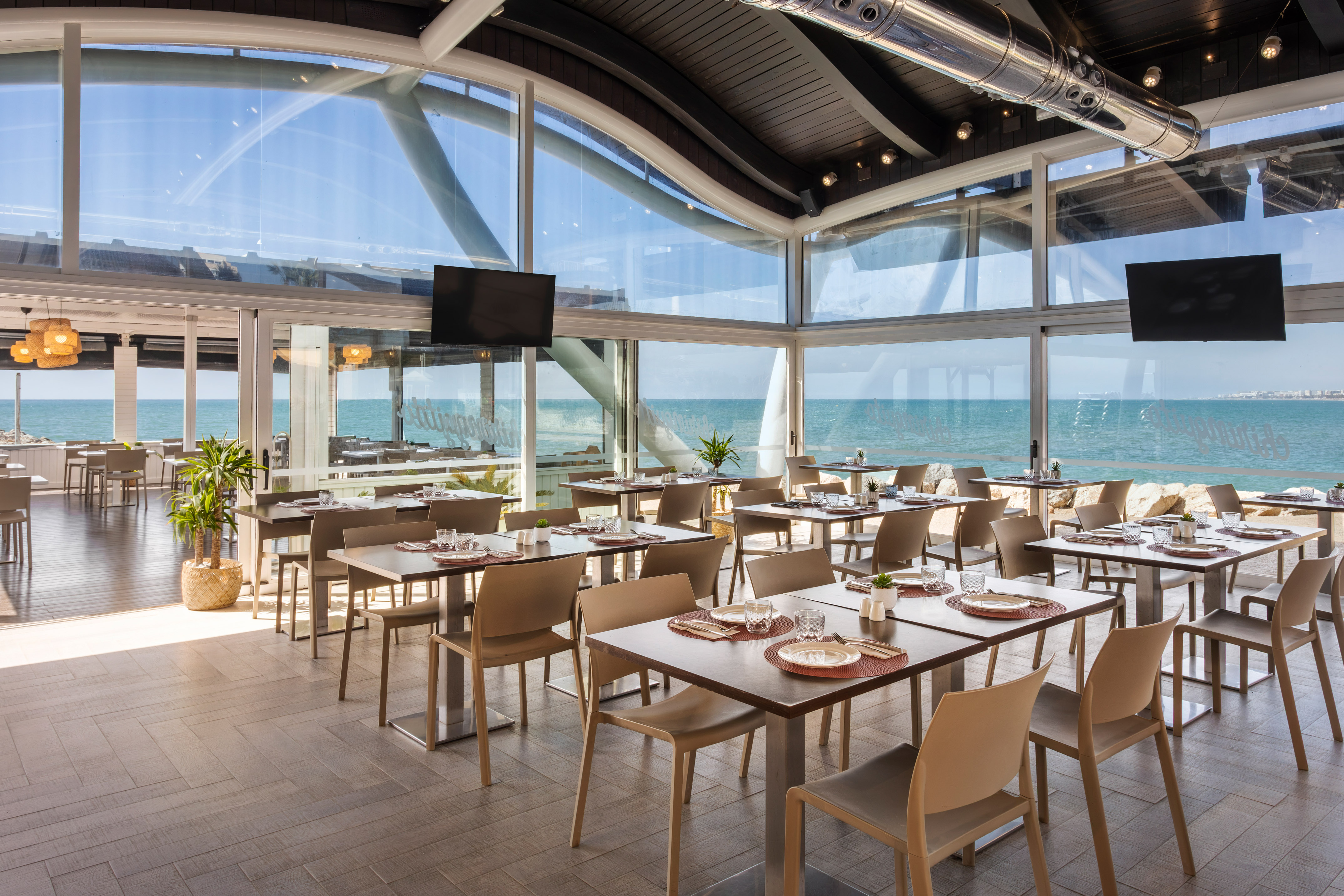 Modern oceanfront restaurant with set tables, large windows, and expansive sea view.