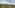 Helicopter flying over green vineyard hills with distant mountains.