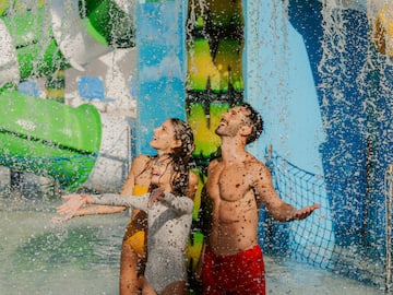 a man and woman in swimsuits under water slide