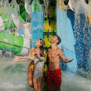 a man and woman in swimsuits under water slide