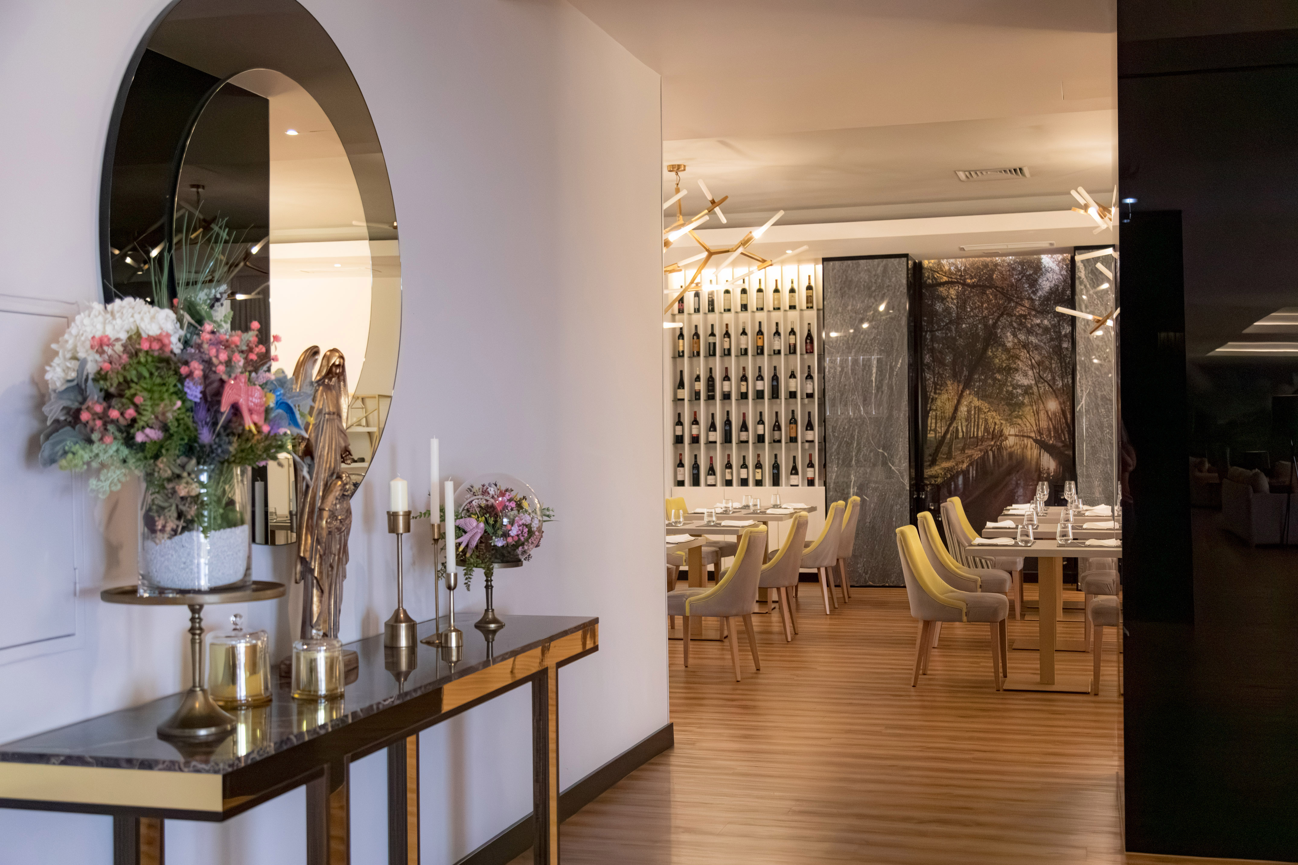 Modern restaurant dining area with elegant entryway decor and prominent wine wall.