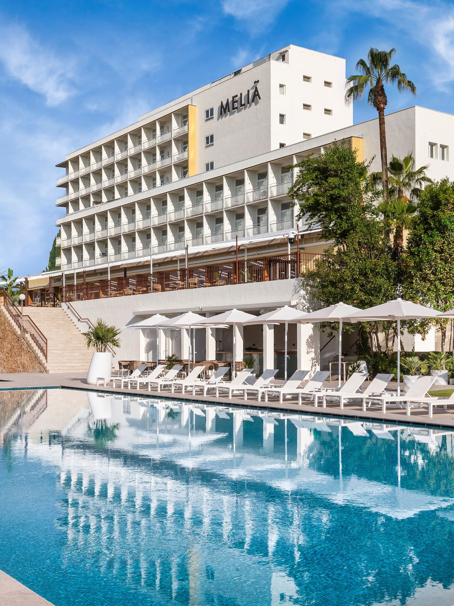 a pool with umbrellas and chairs in front of a building